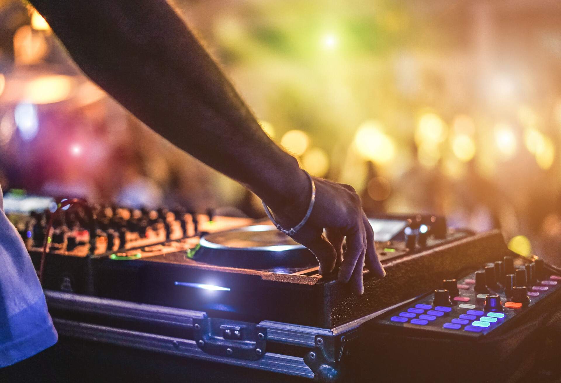 Dj mixing outdoor at beach party festival with crowd of people in background - Summer nightlife view of disco club outside - Soft focus on hand - Fun ,youth,entertainment and fest concept