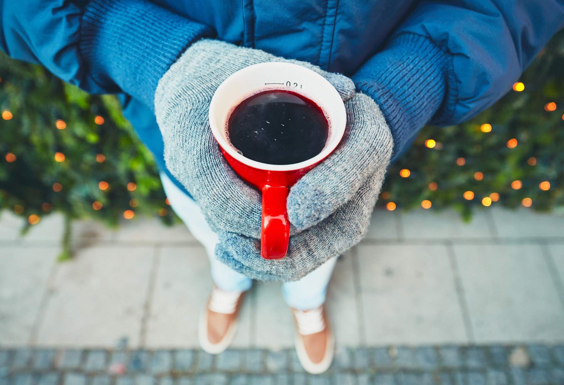 Man holding cup of the hot wine at the Christmas market - Munich, Germany - selective focus