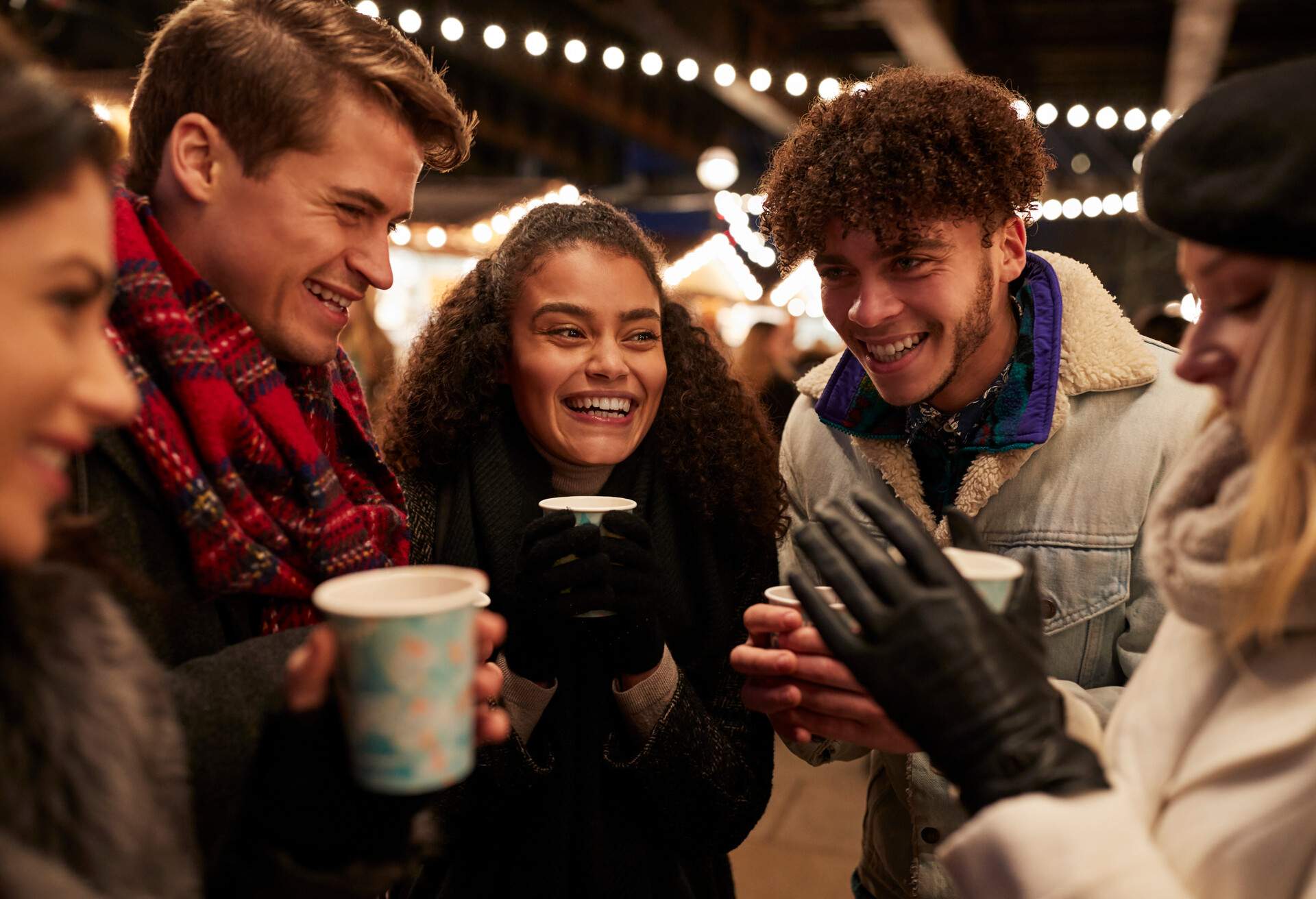 Group Of Friends Drinking Mulled Wine At Christmas Market