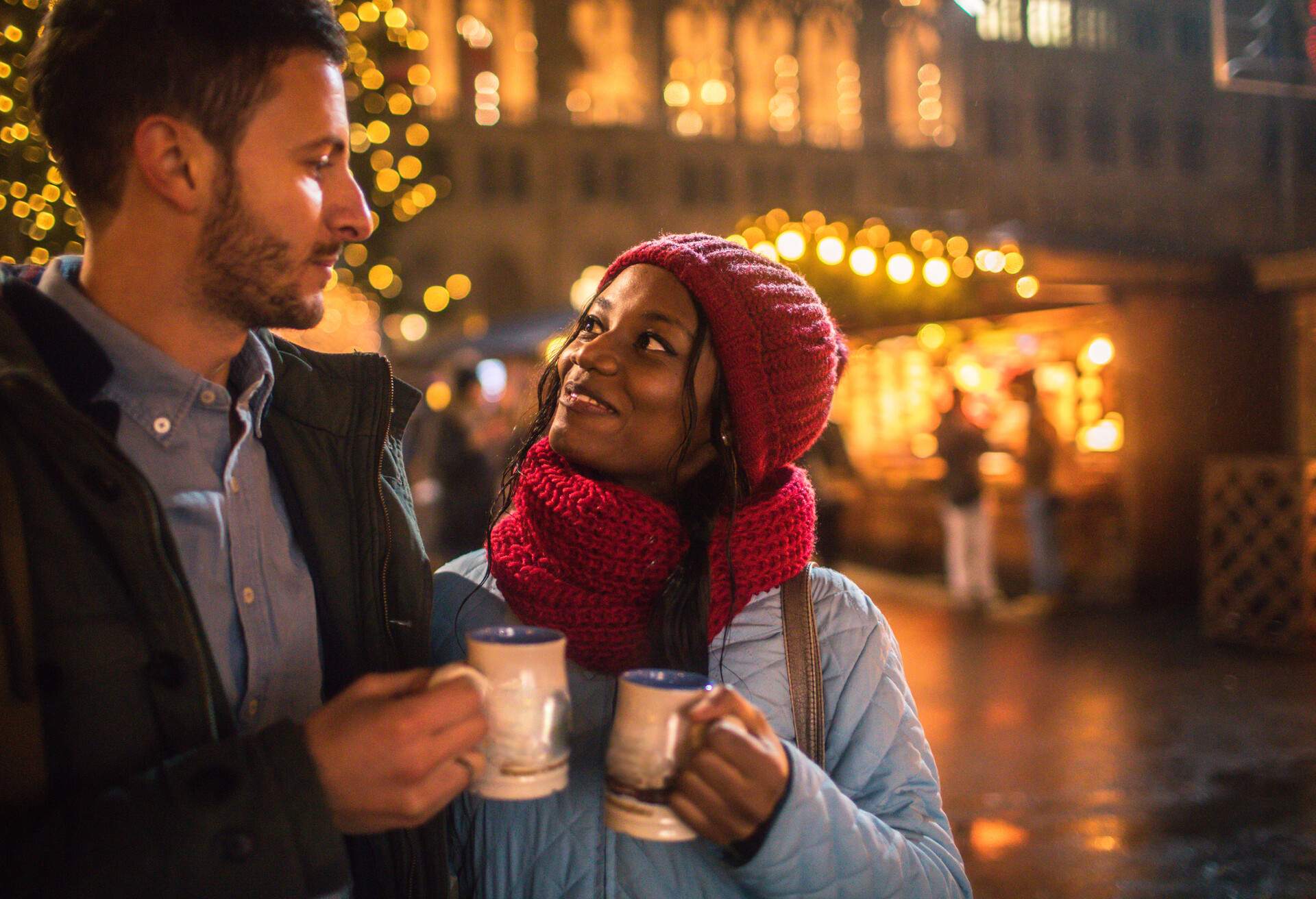 Photo of a young couple having mulled wine on Christmas Market, during Christmas Holidays