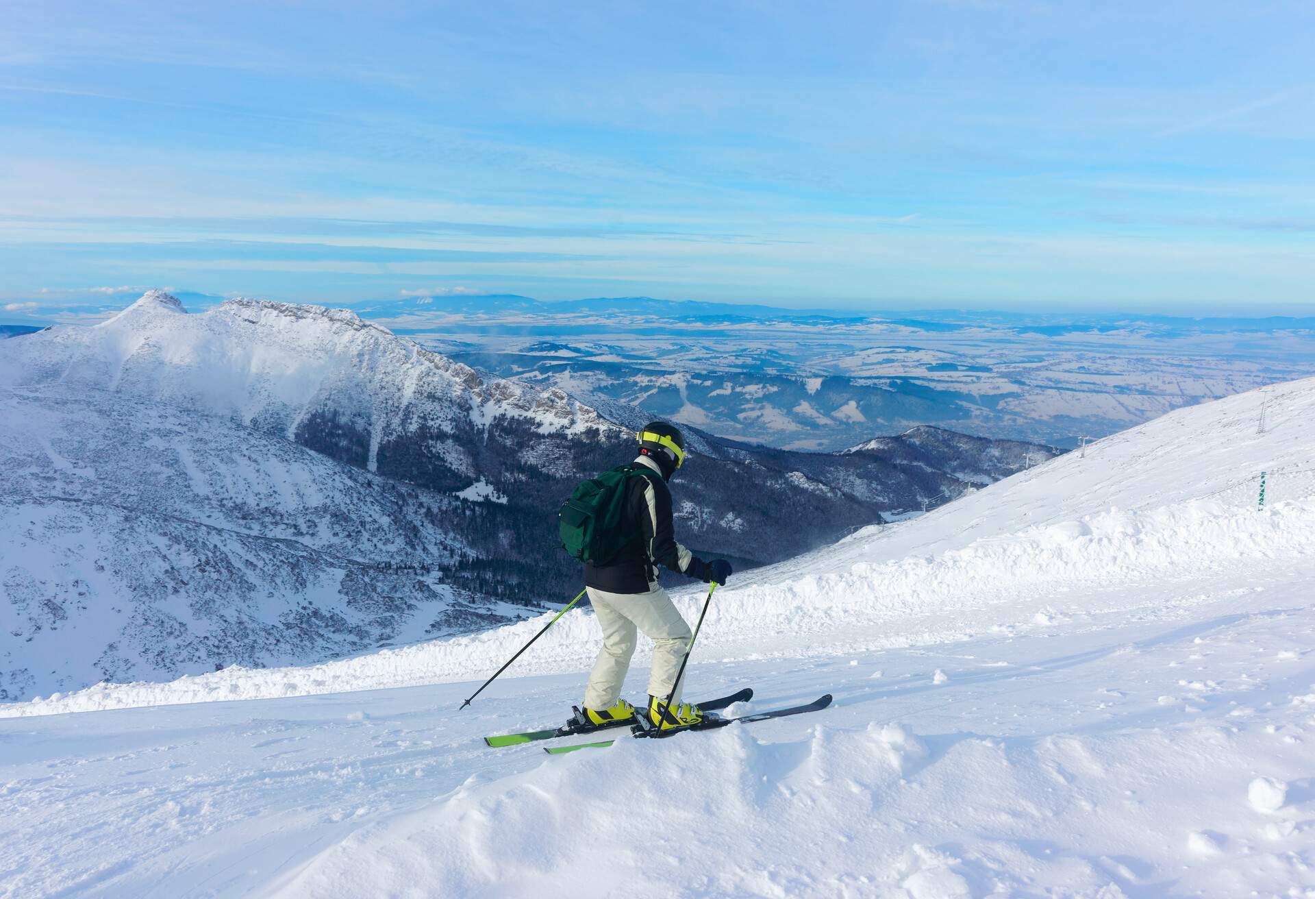 A person skiing down a snowy slope while gazing at the snowy mountains.