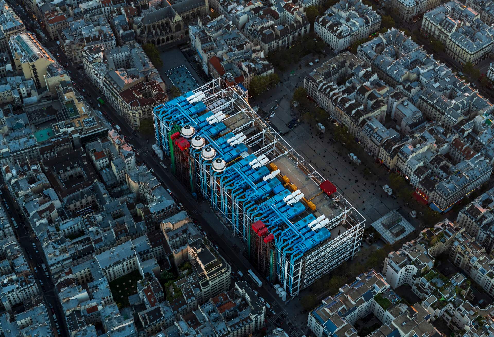 Aerial flying over Paris France looking the city below and Le Centre Pompidou, the streets and buildings, view from a helicopter on a beautiful clear late afternoon before sunset