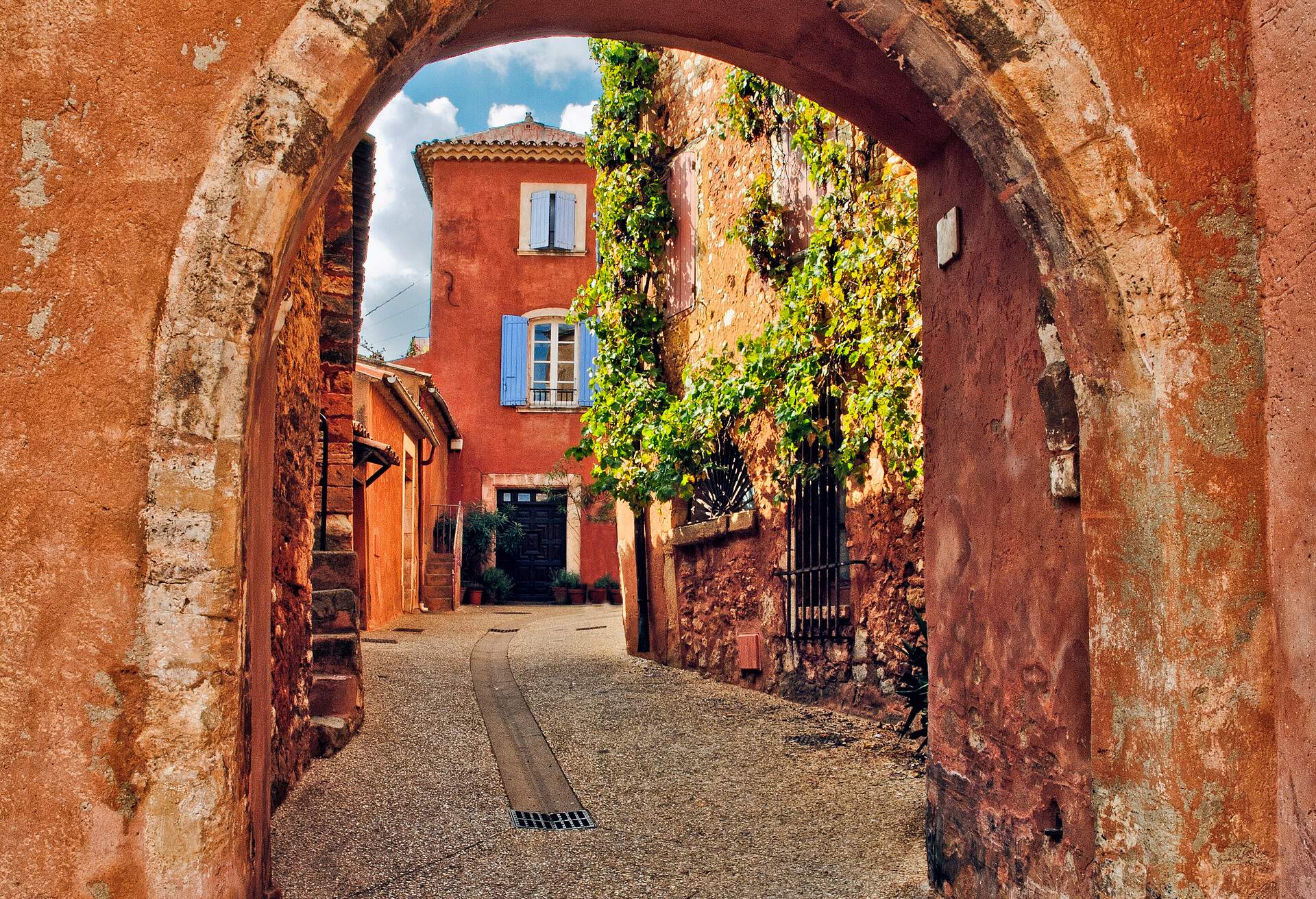 A view through the archway in the base of the clock tower in Roussillon, a hill town built out of red, yellow and orange ochre in the Luberon, the mountainous area in the northern part of Provence, France.