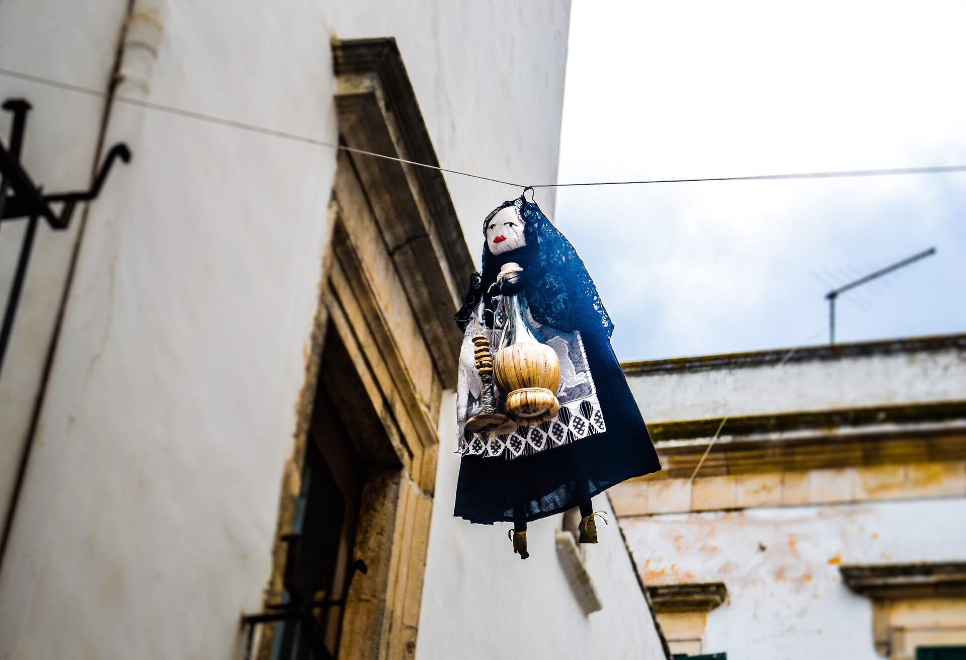 A small doll looking like a woman attached to a string between buildings