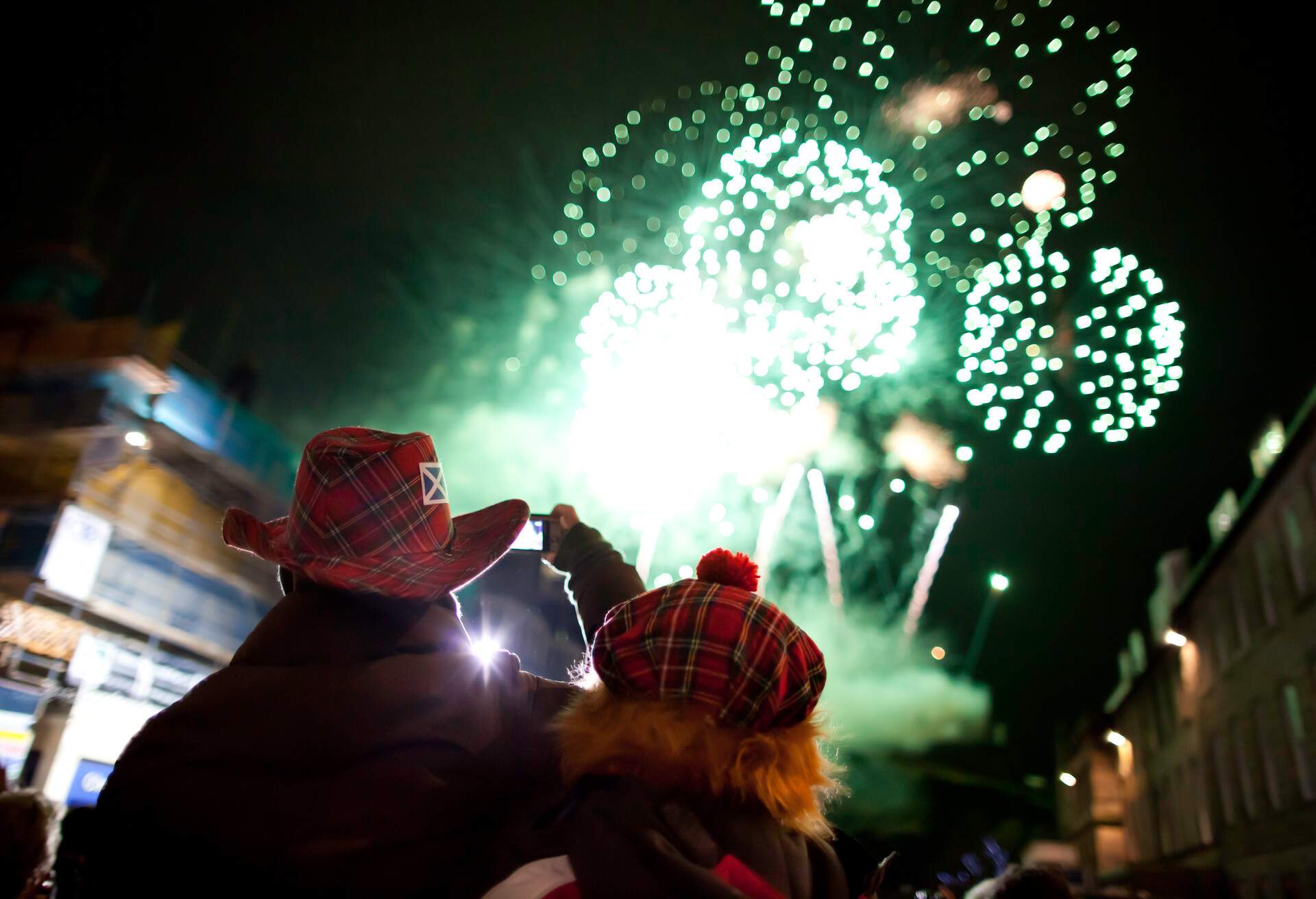 Two people with red hats looking at some fireworks
