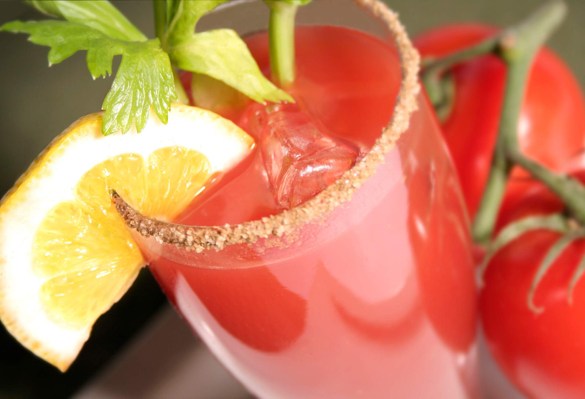 A delicious Tomato Juice Coktail (Bloody Caesar or Bloody Mary), served with a slice of lemon and a branch of celery, with ice cubes.