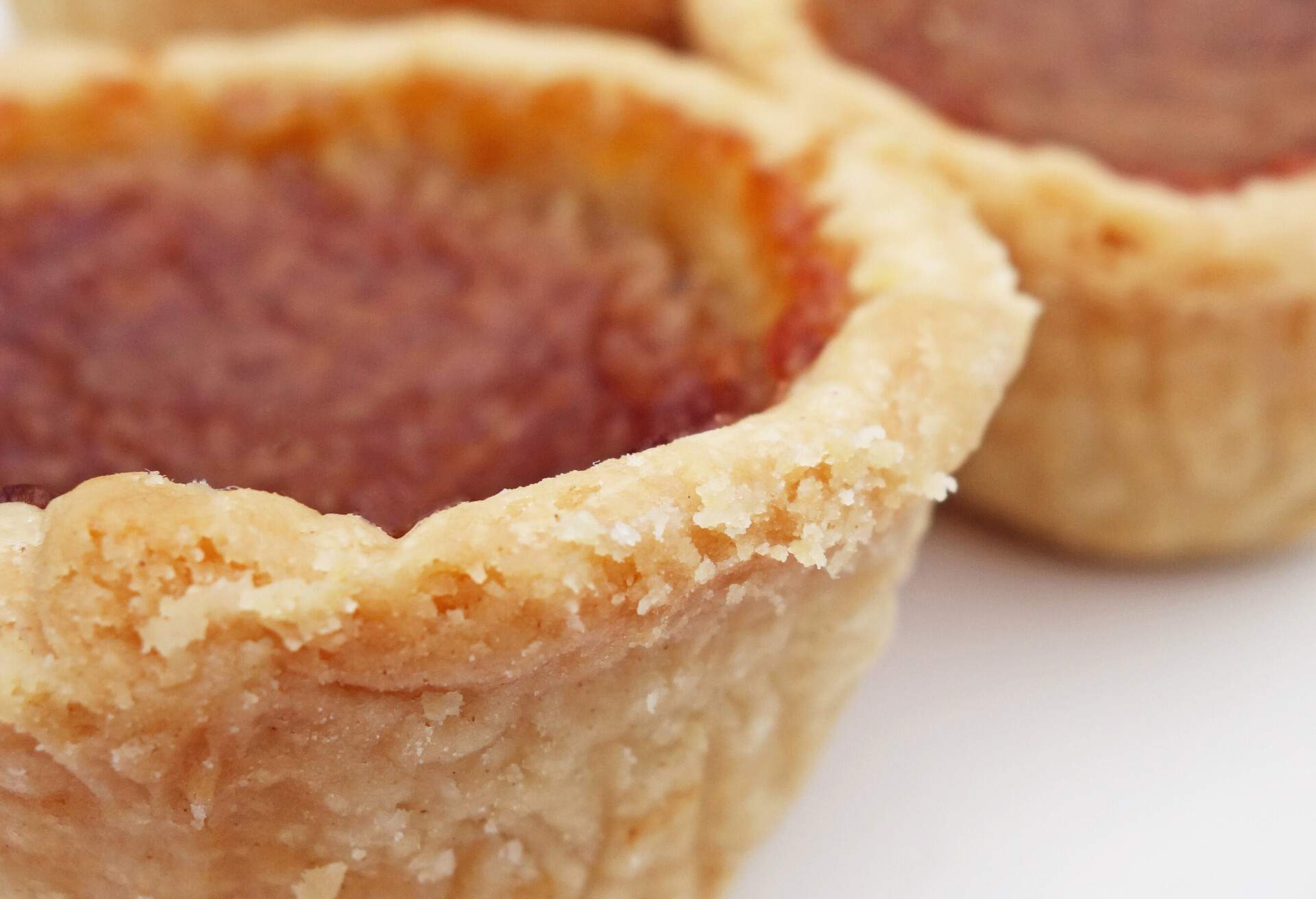 Close Up view of butter tarts with selective focus on crust, blurred background photo.