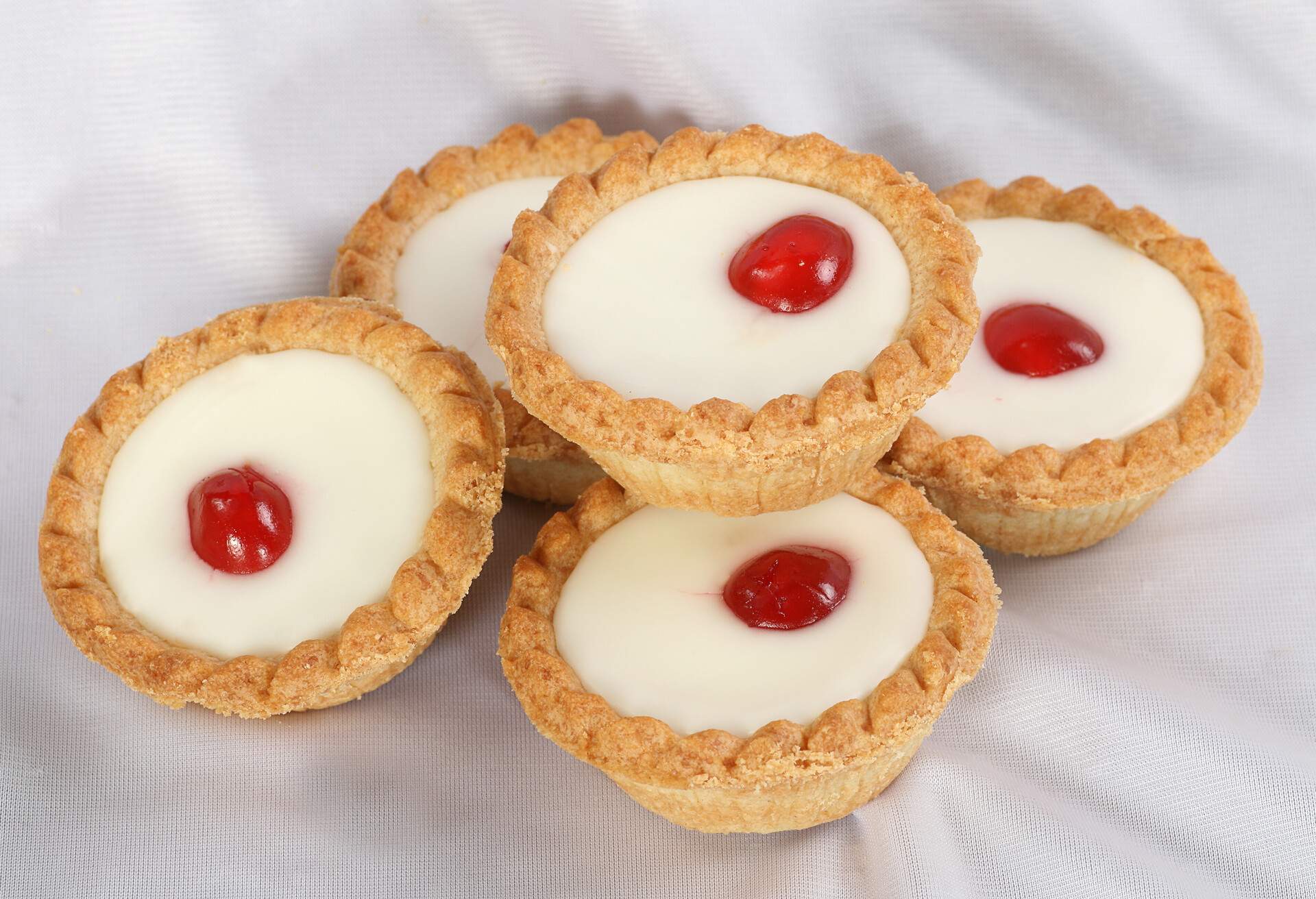 five cherry bakewell cakes on a white cloth