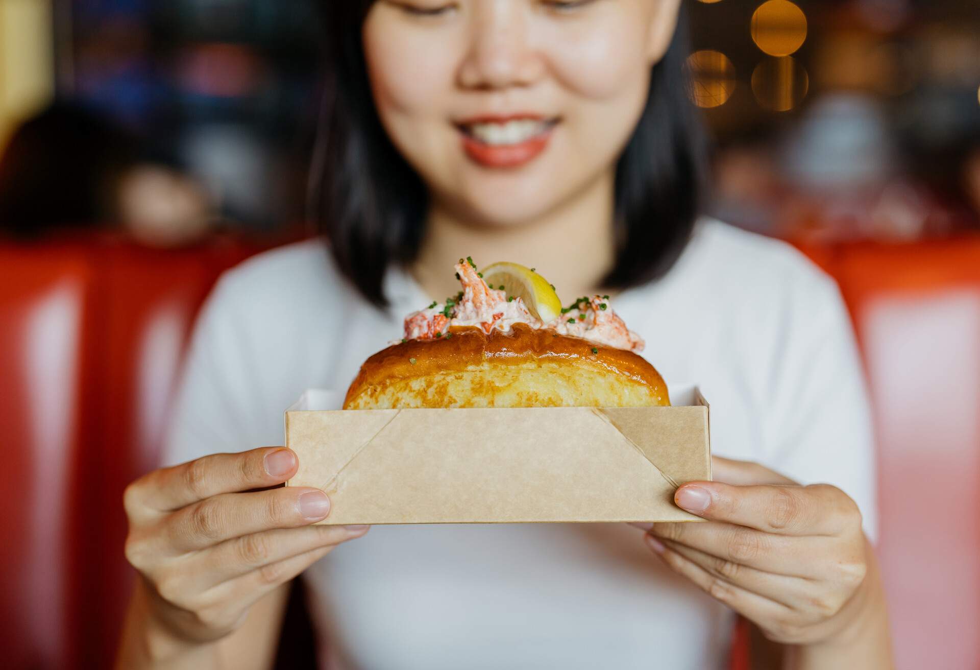 Image of an Asian Chinese woman hand holding and ready to eat lobster roll in restaurant