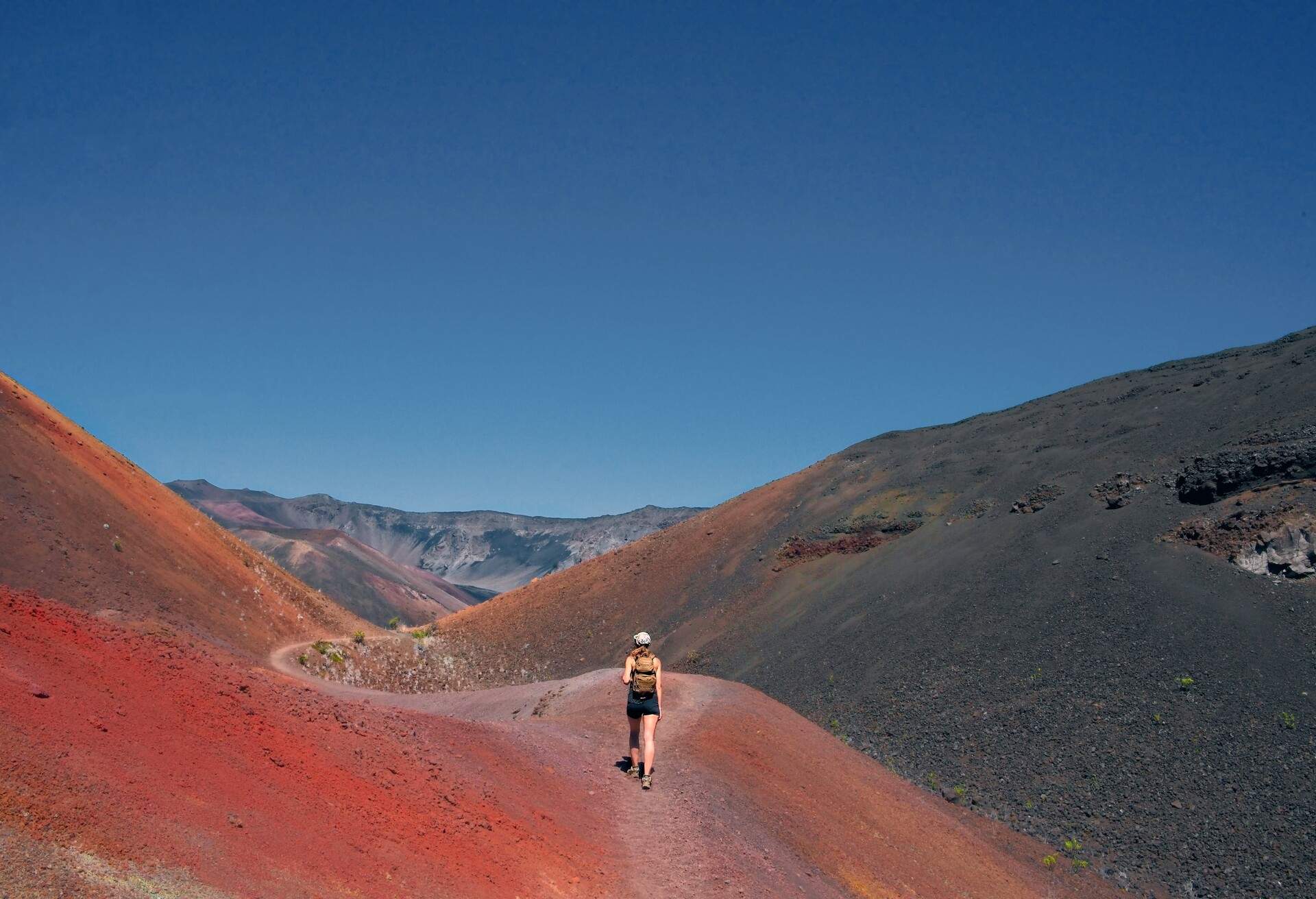 Girl hikes through the colourful sands in Haleakalā National Park on the Sliding Sands Trail in Maui, Hawaii.