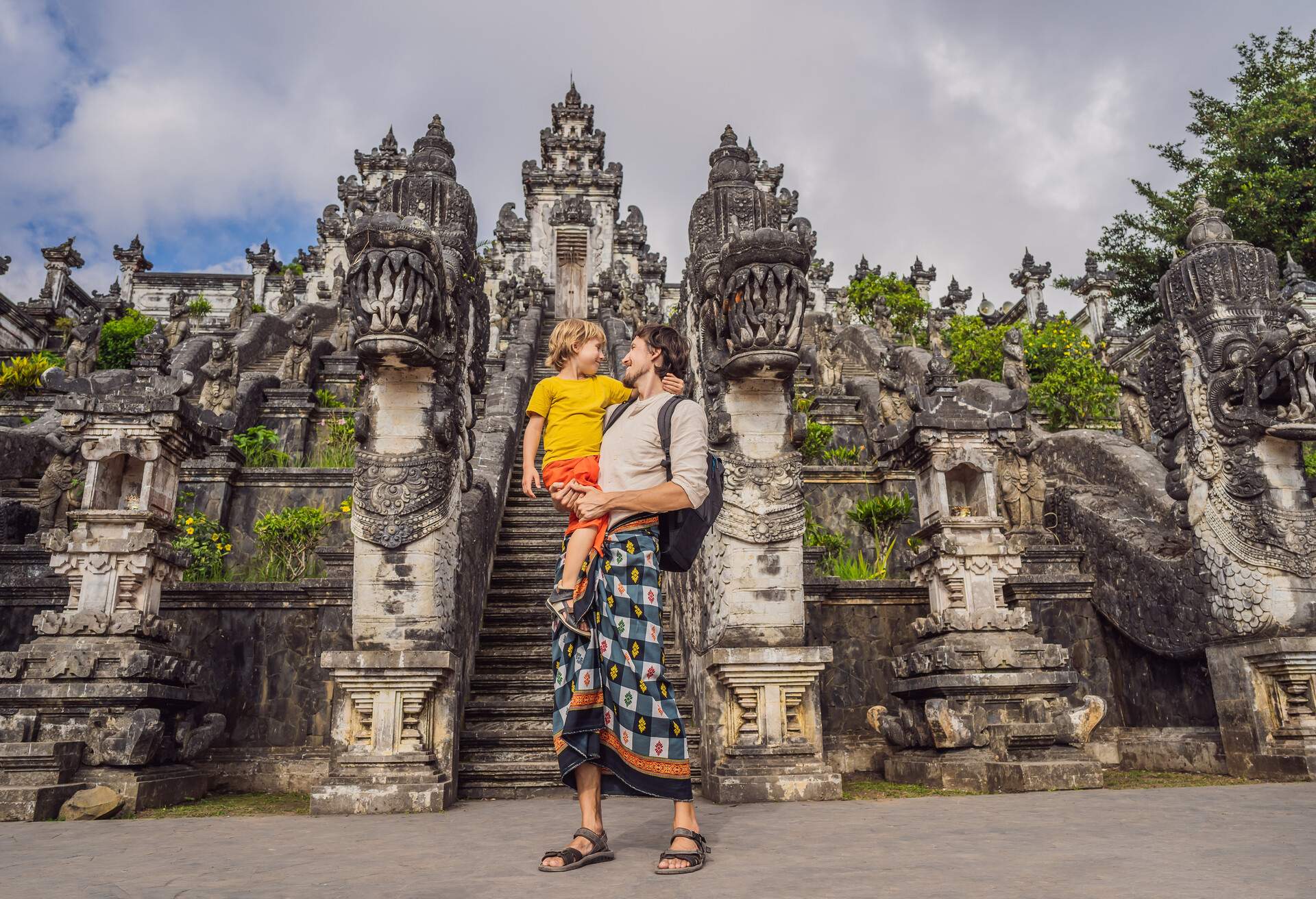 Dad and son tourists on background of Three stone ladders in beautiful Pura Lempuyang Luhur temple.Paduraksa portals marking entrance to middle sanctum jaba tengah of Pura Penataran Agung, Bali. Traveling with children concept. Kids friendly place. 