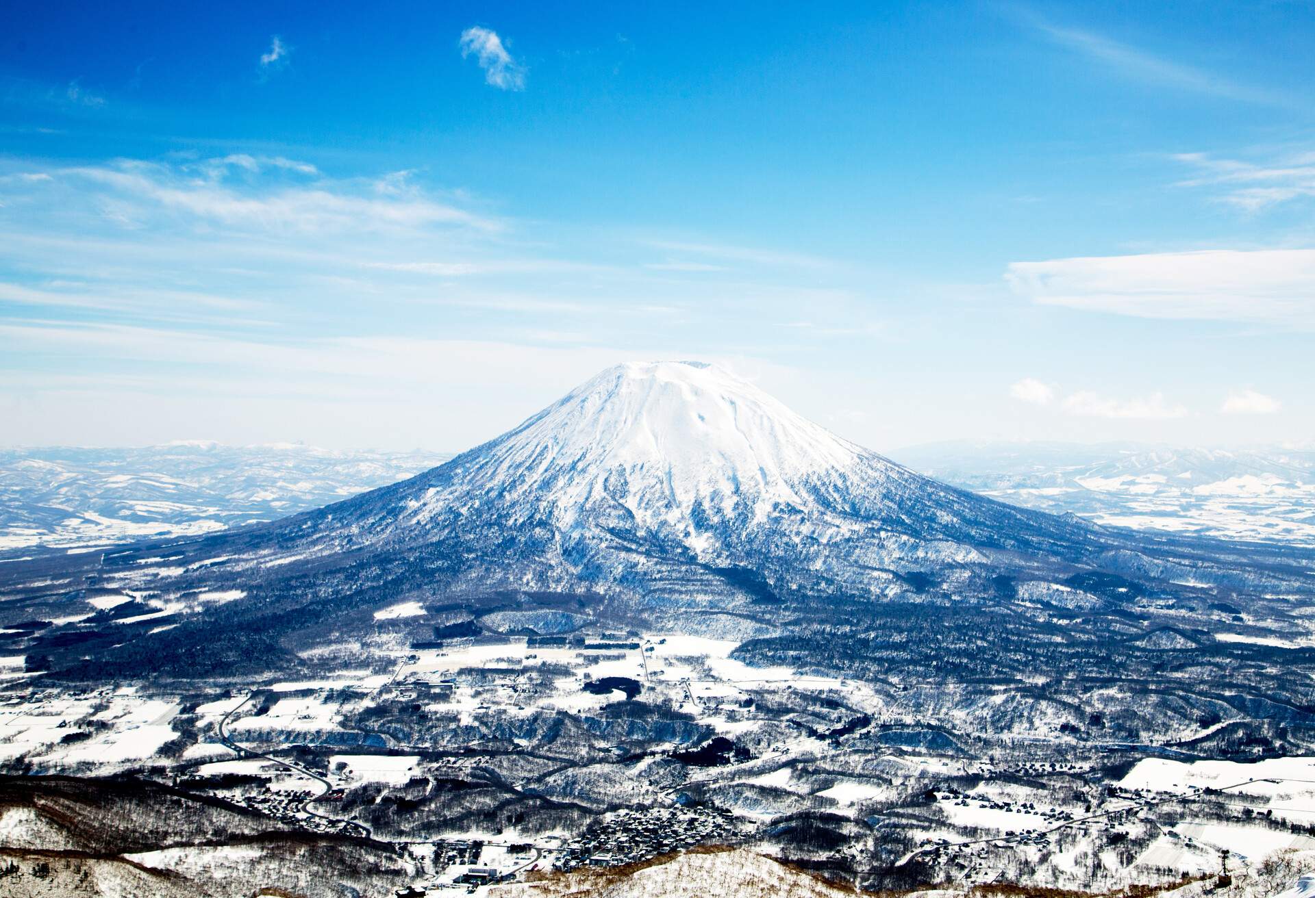 The almost perfect cone-shaped active stratovolcanic landscape is covered with snow.