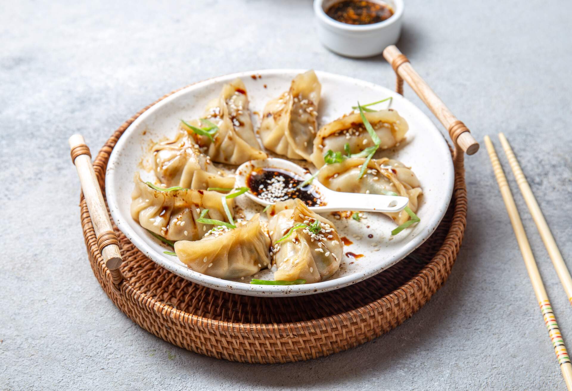 Asian Japanese and Korean gyoza dumplings on white plate, gray background.