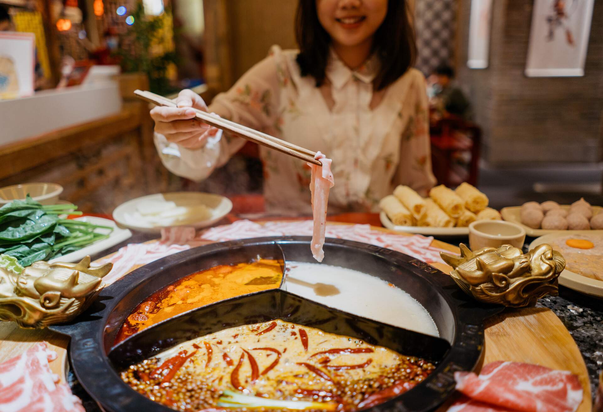 An Asian Chinese woman boiling a pork slice with hot pot soup