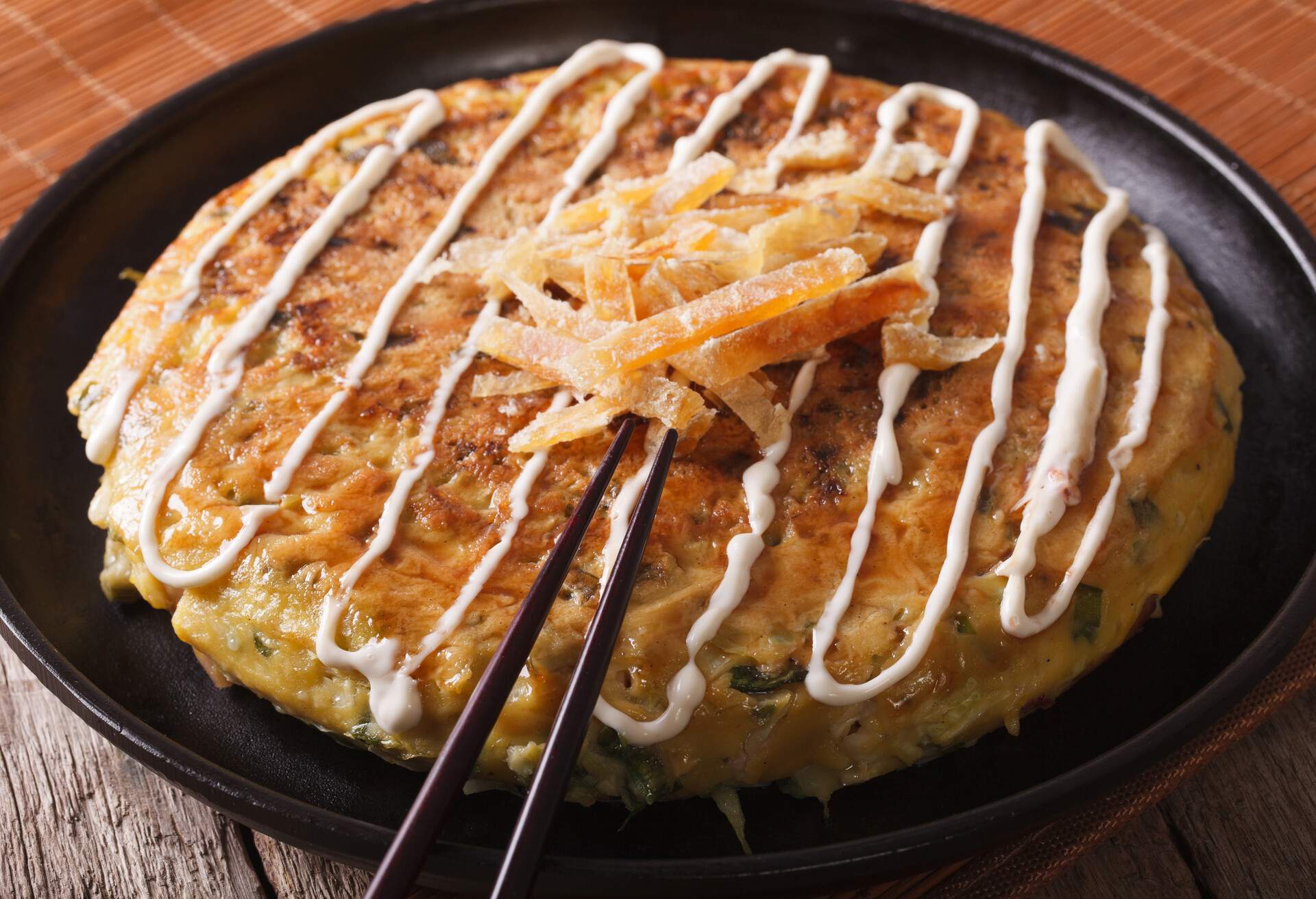 Japanese fast food: okonomiyaki on a plate close-up and chopsticks