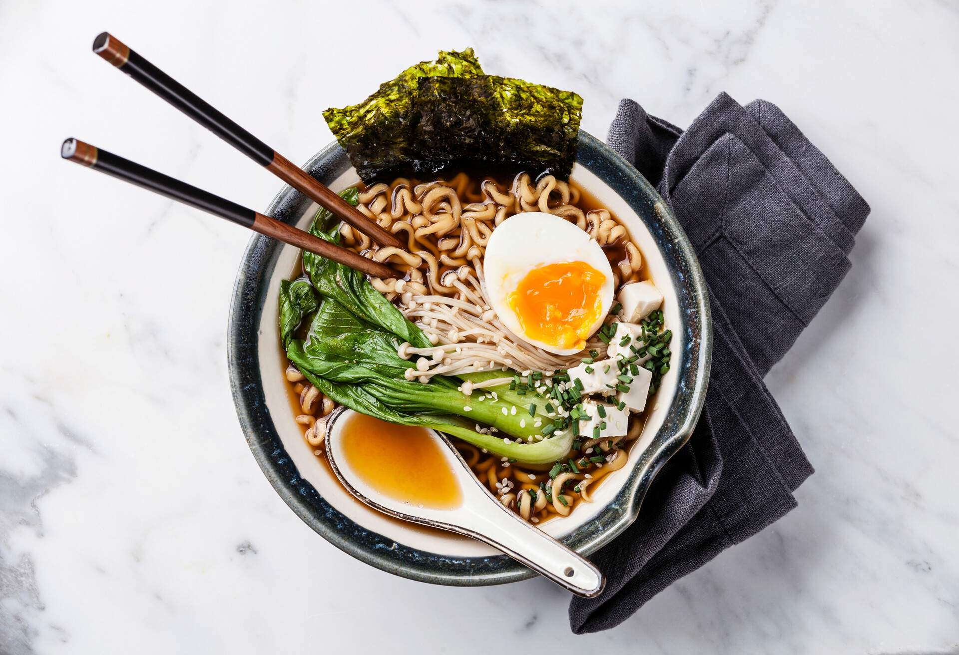 Miso Ramen Asian noodles with egg, enoki and pak choi cabbage in bowl on white marble background