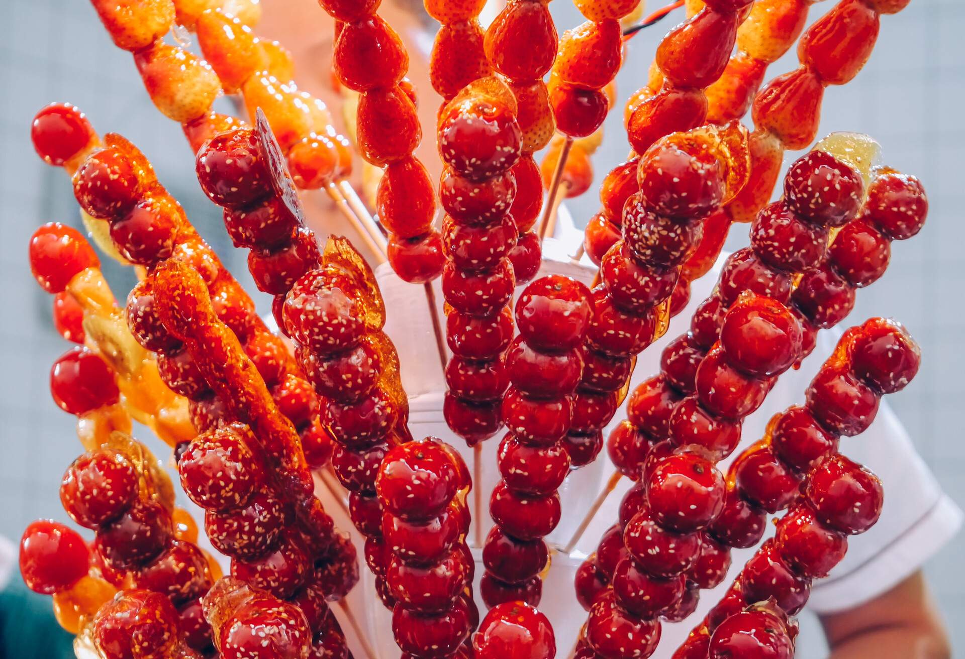 Chinese toffee apples and candied strawberries in market stall.