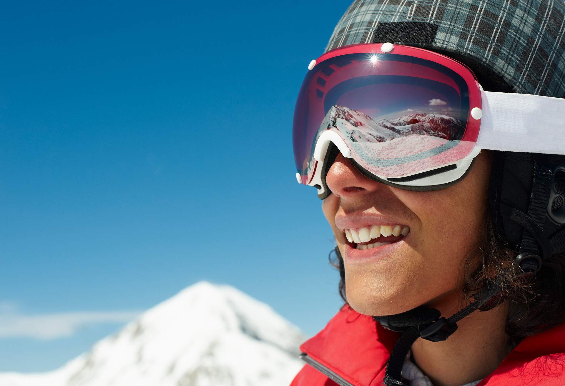 Male Skier wearing goggles, looking over Bansko Mountains smiling 