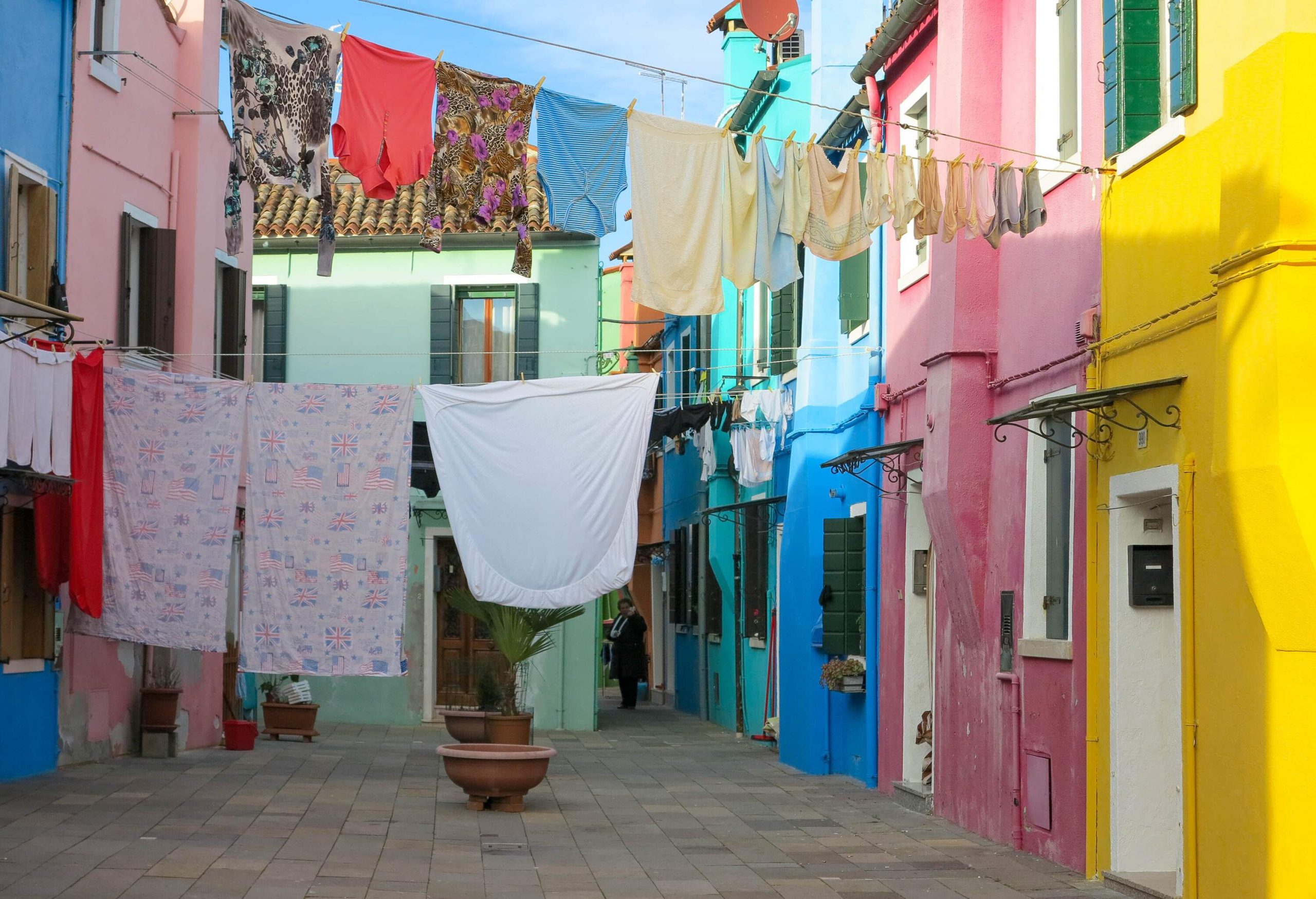 Laundry drying on the clothesline across the street bordered by pastel-coloured houses.