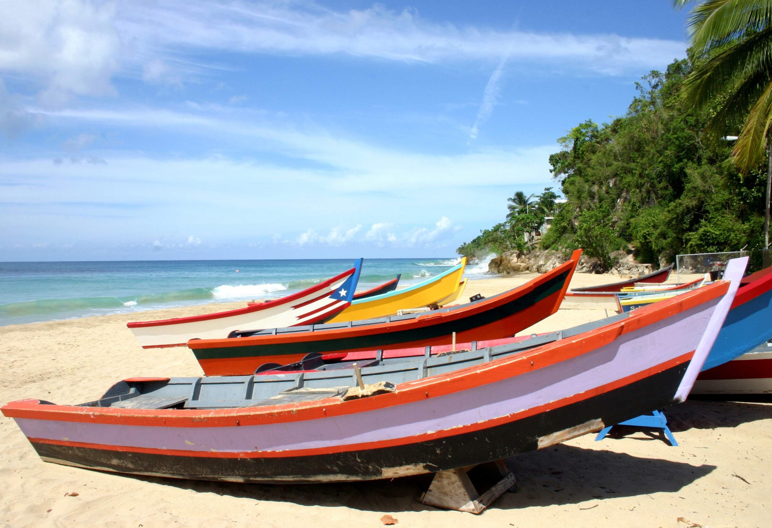 Colourful fishing boats lined up on the empty shore alongside the calm sea.