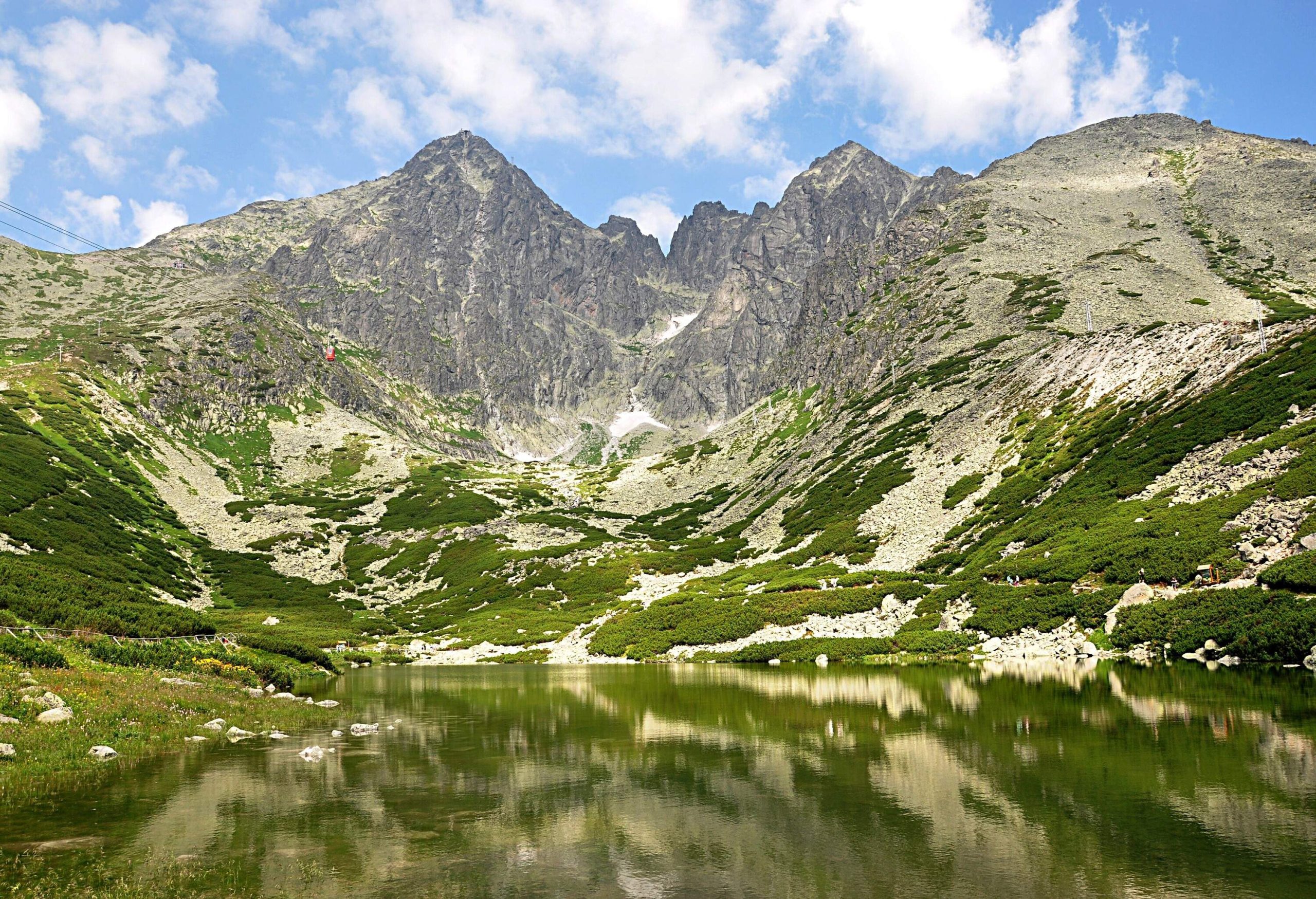 A river's glassy waters mirroring the high mountains looming over it.