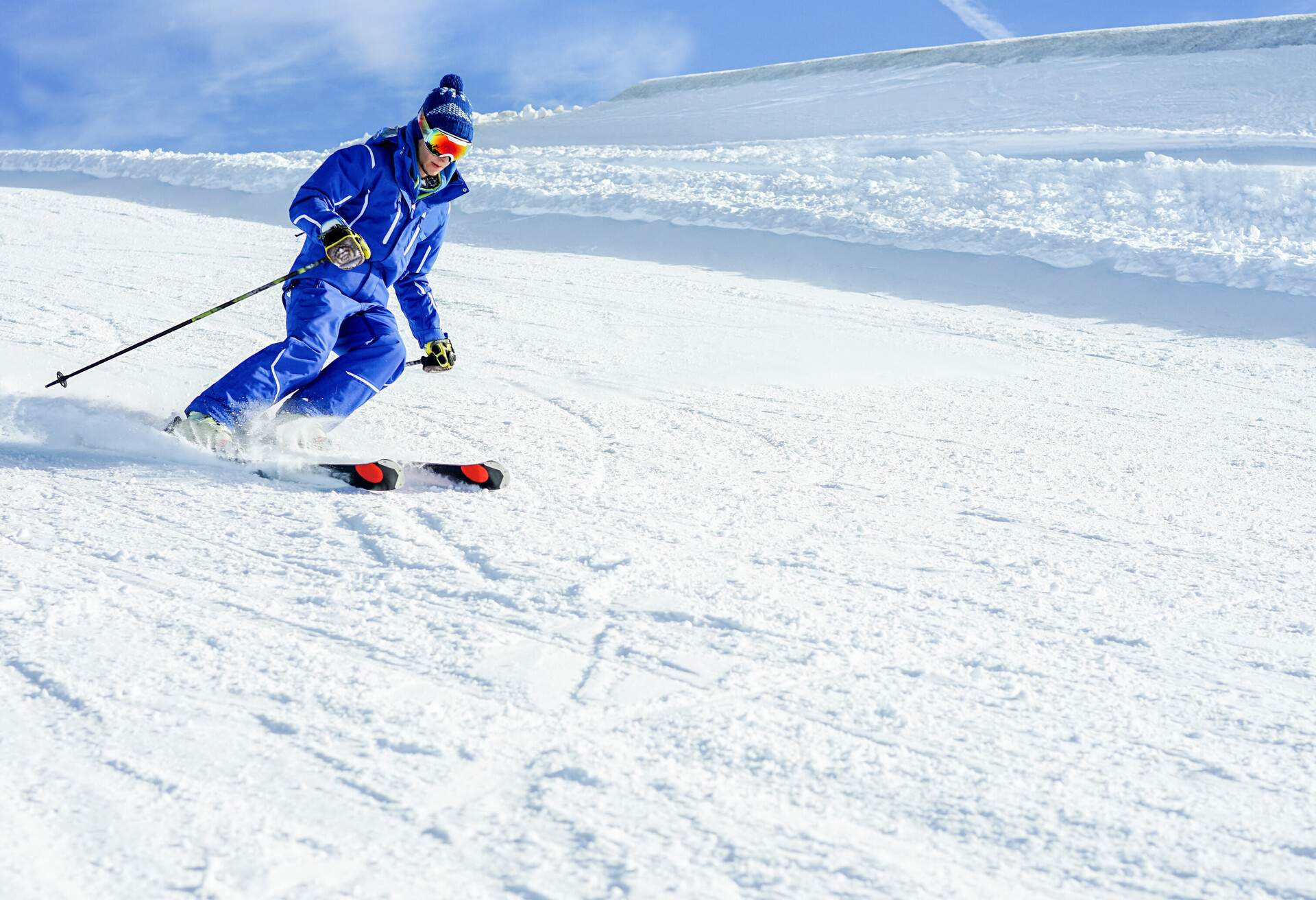 A man in a blue ski outfit sweeping through a piste.