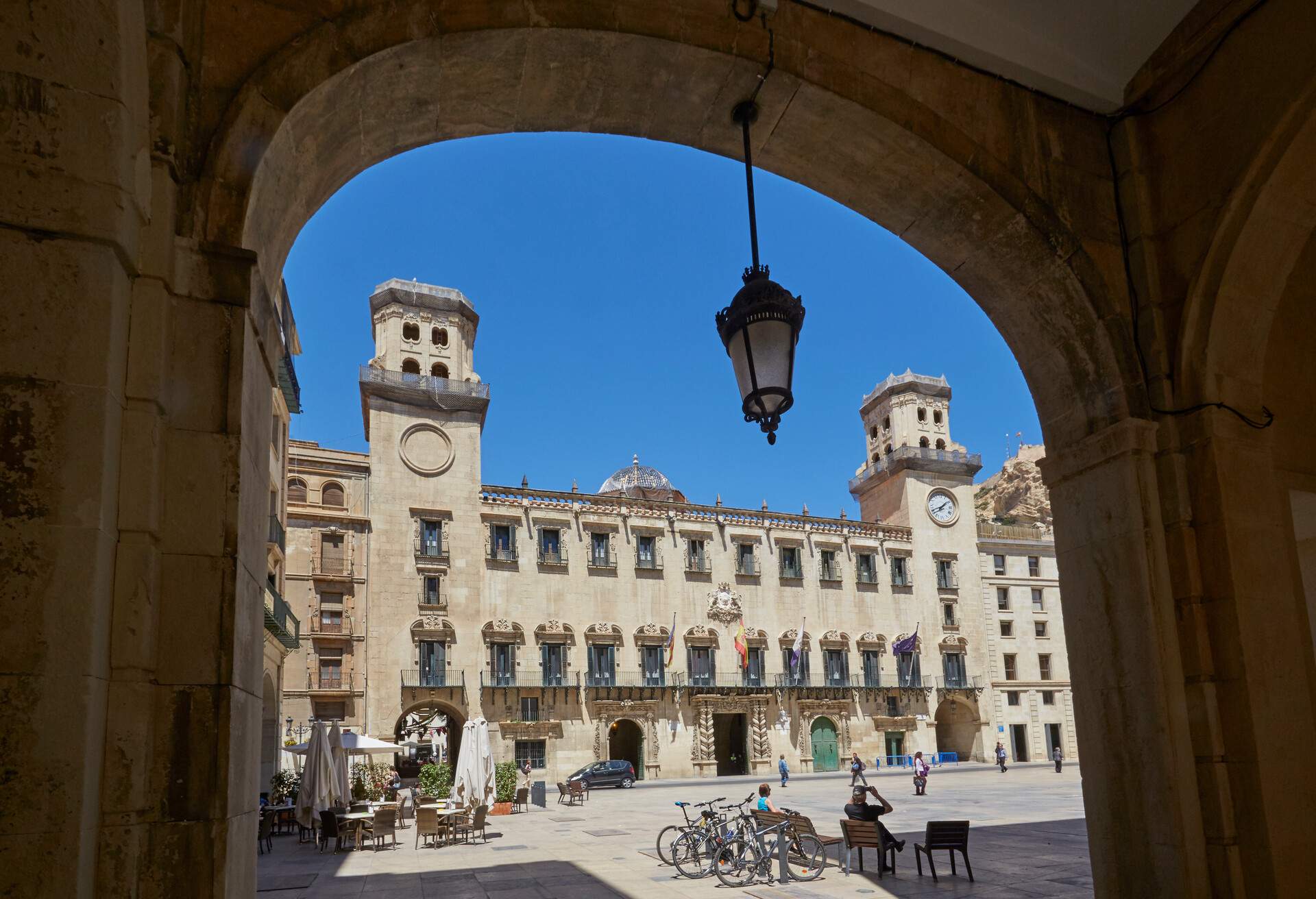 Facade of the Alicante City Hall (Ayuntamiento de Alicante) with arch in foreground under blue skies. Spain