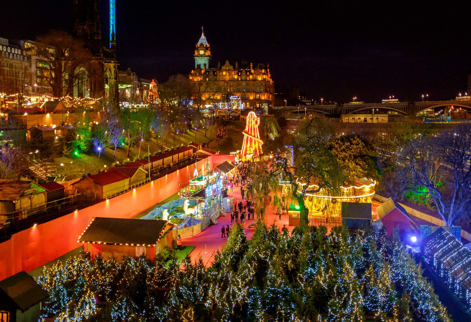 Scotland, Edinburgh, Princes Street Christmas Market. A traditional European Christmas Market located along Princes Street with the Scotts Monument and Balmoral Clock Tower in view.