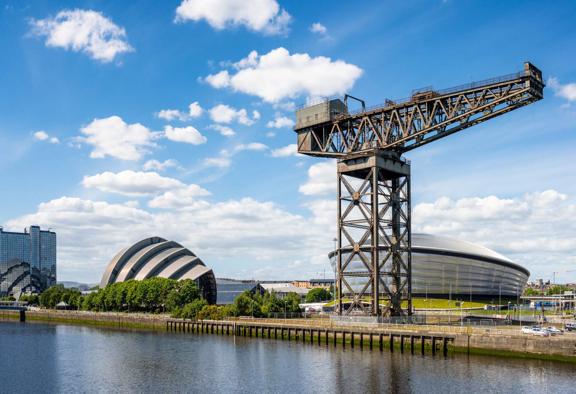 A panoramic view along the north bank of the River Clyde in Glasgow, with hotels, the Hydro, the Armadillo and with the skyline dominated by the historic Finnieston Crane.
