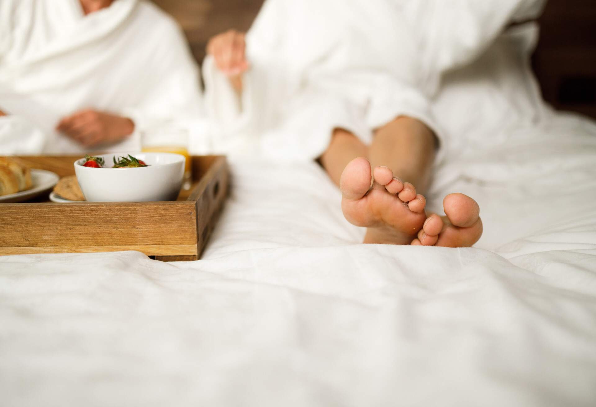 Close up of unrecognizable woman's feet during morning time on a bed. Copy space.