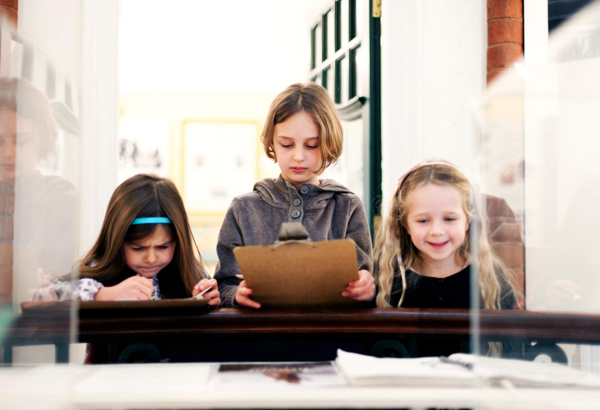 Young girls standing close to an exhibit in a glass display case.