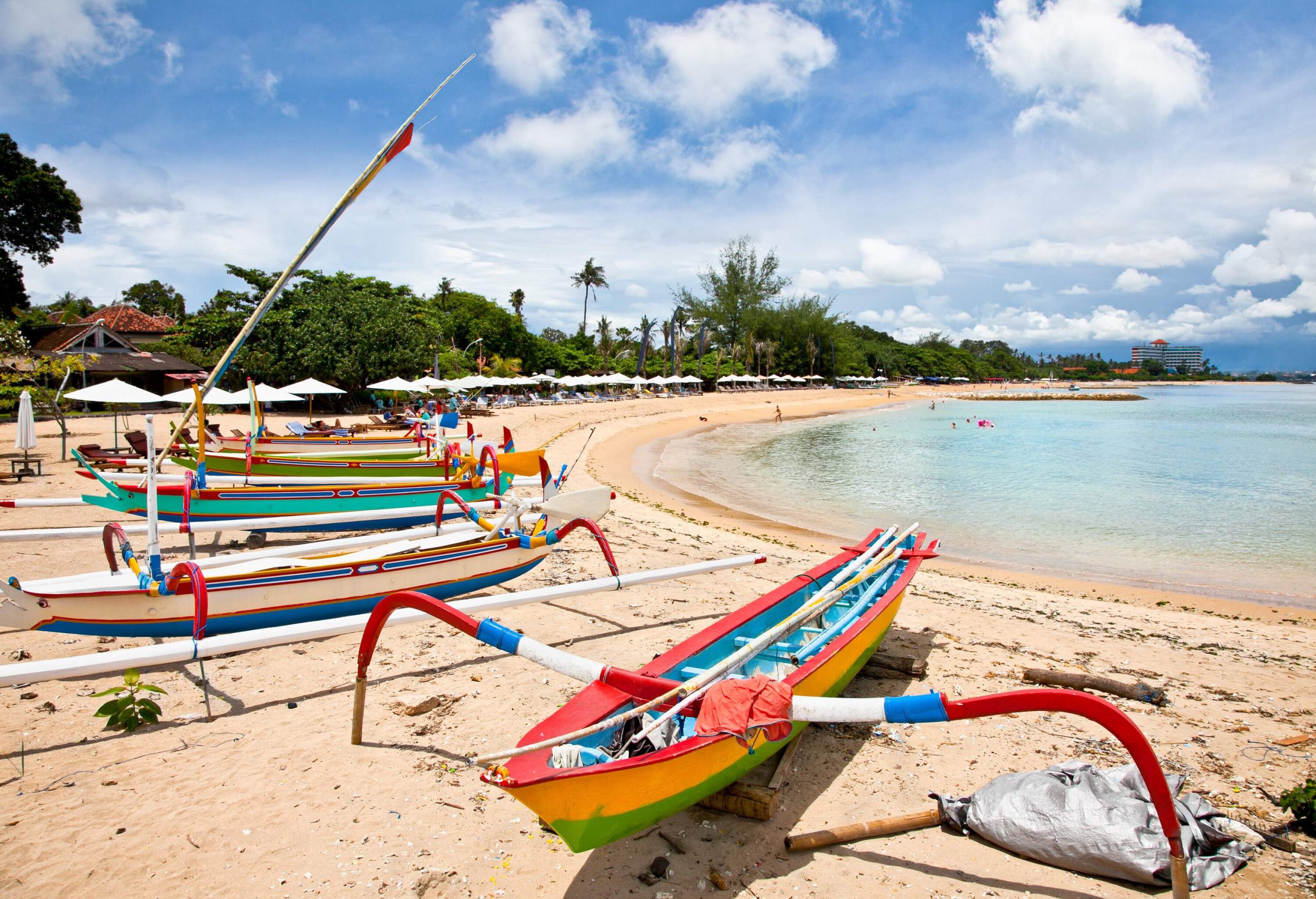 Colourful fishing boats docked on the sand across a crystal-clear sea.