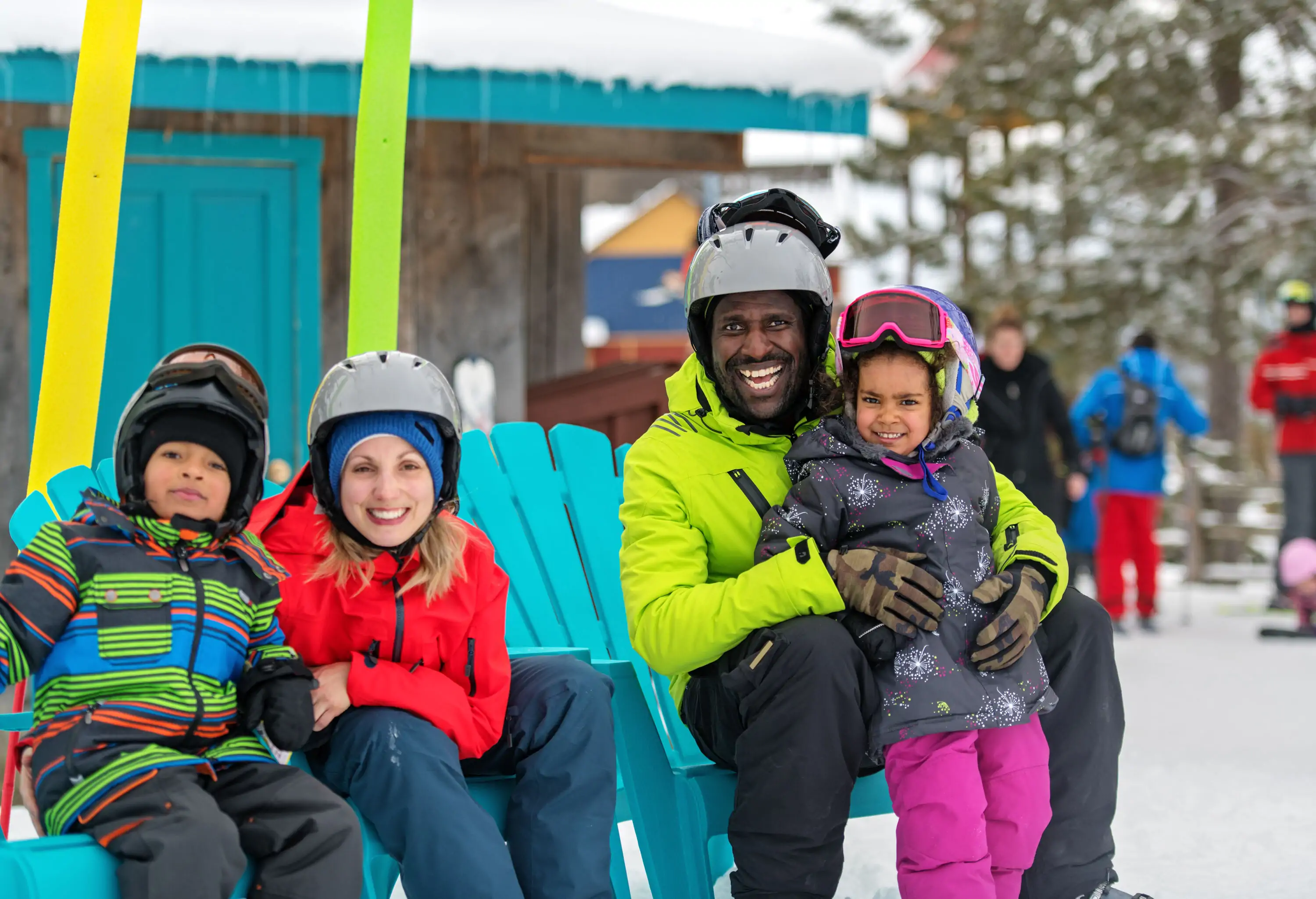 A family of four in colourful winter clothes are smiling.