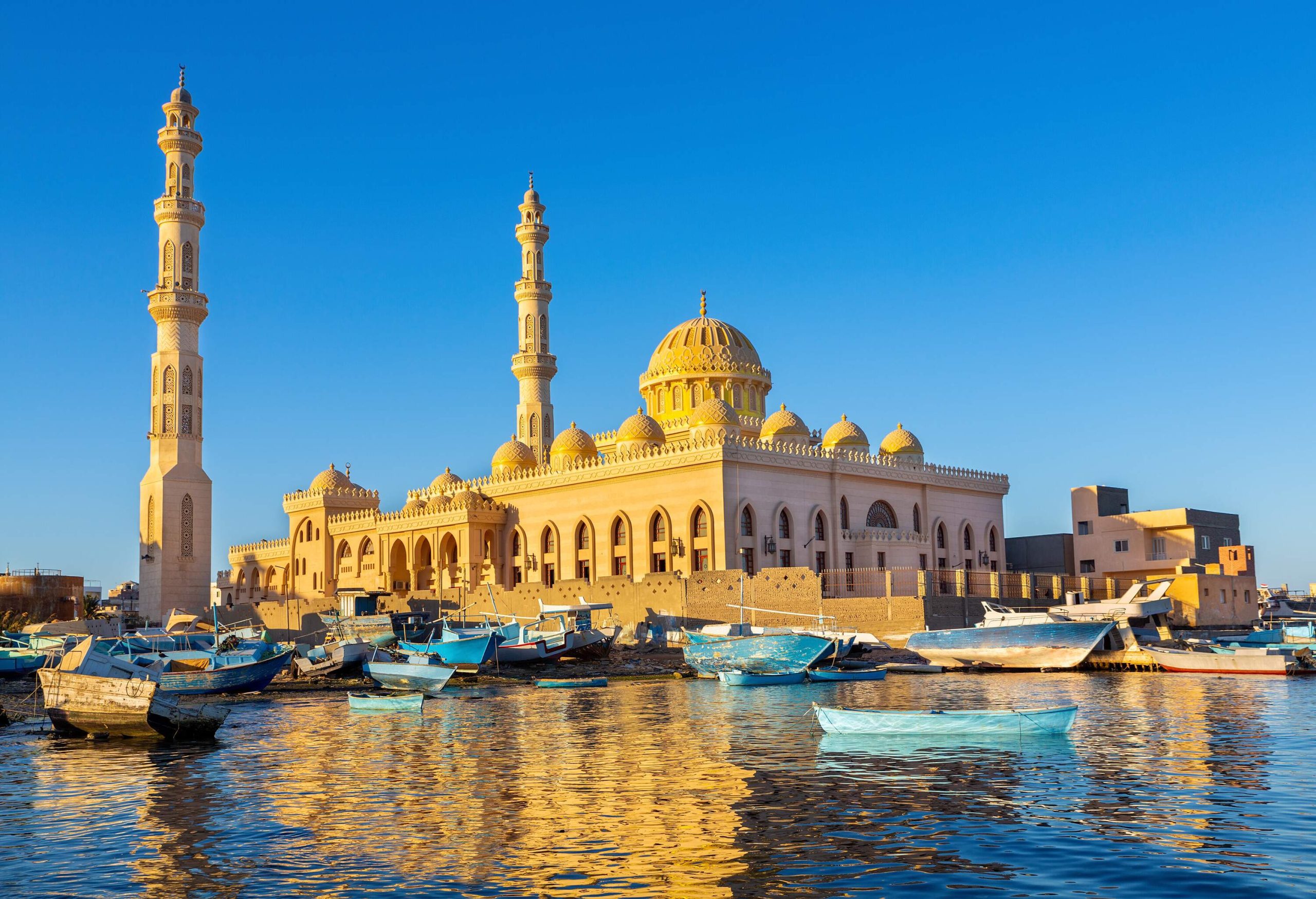 A resplendent golden mosque overlooks a tranquil sea dotted with quaint fishing boats.