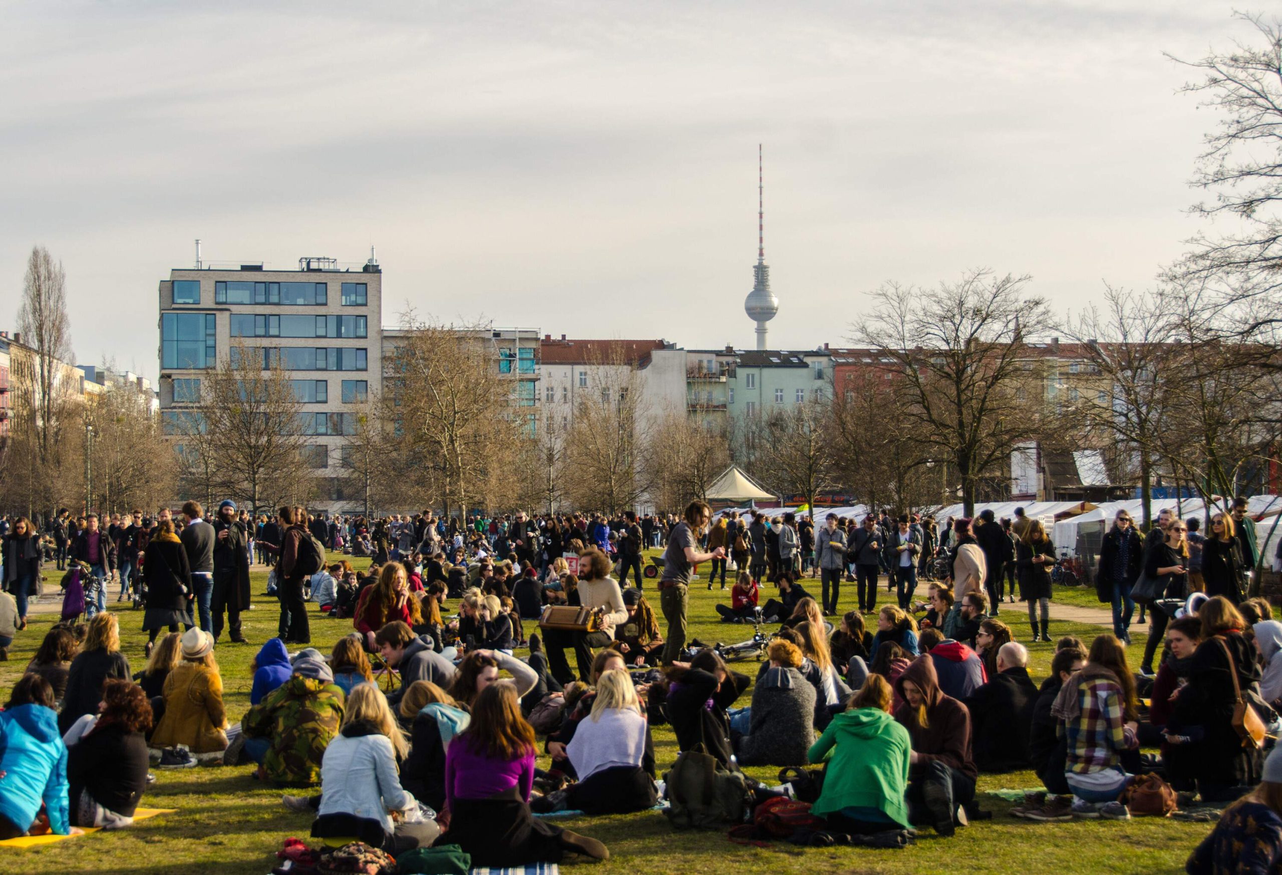 A swarm of people hanging out and enjoying a nice day at a park.