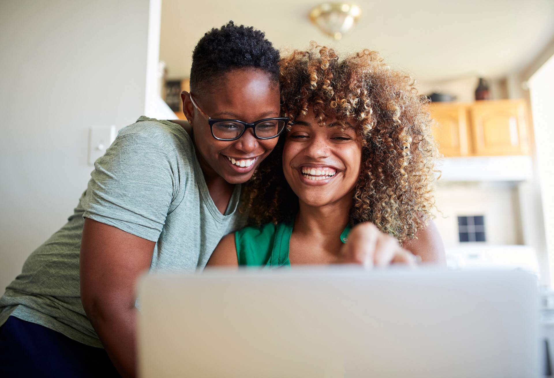 Two females smiling as they look at a laptop screen. 