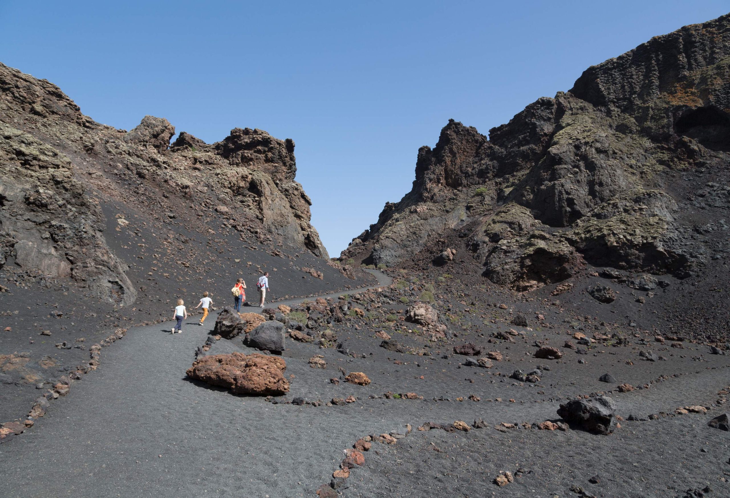 A family of four people walking on the trail of the volcanic mountain.