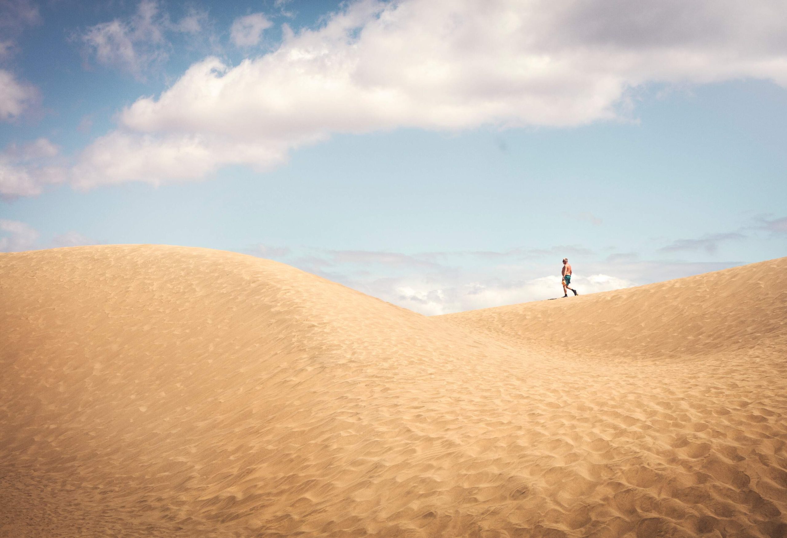 A person walking on deserted sand dunes.