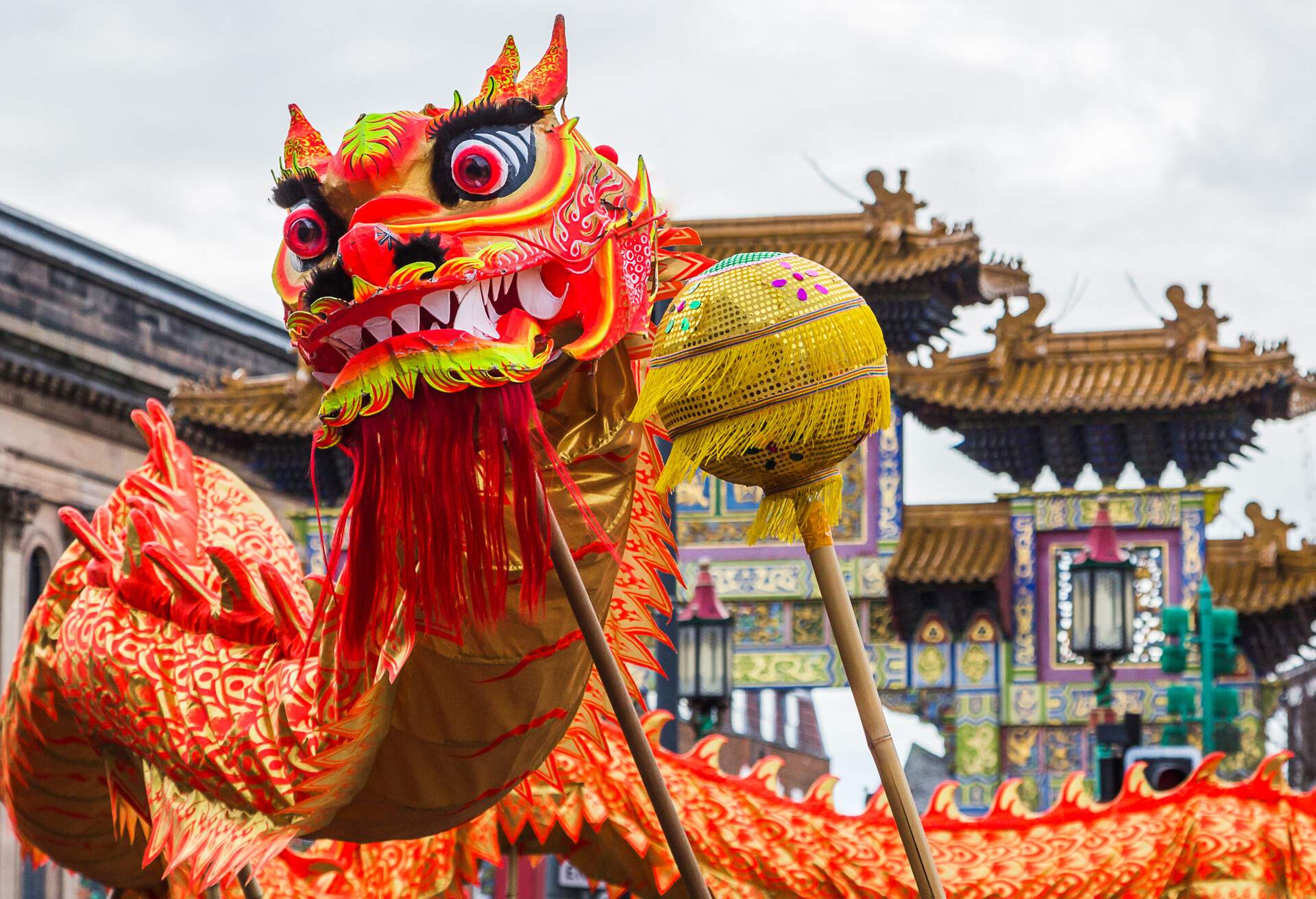 A vibrant dragon with ornamental pieces dancing in front of a Chinese temple.