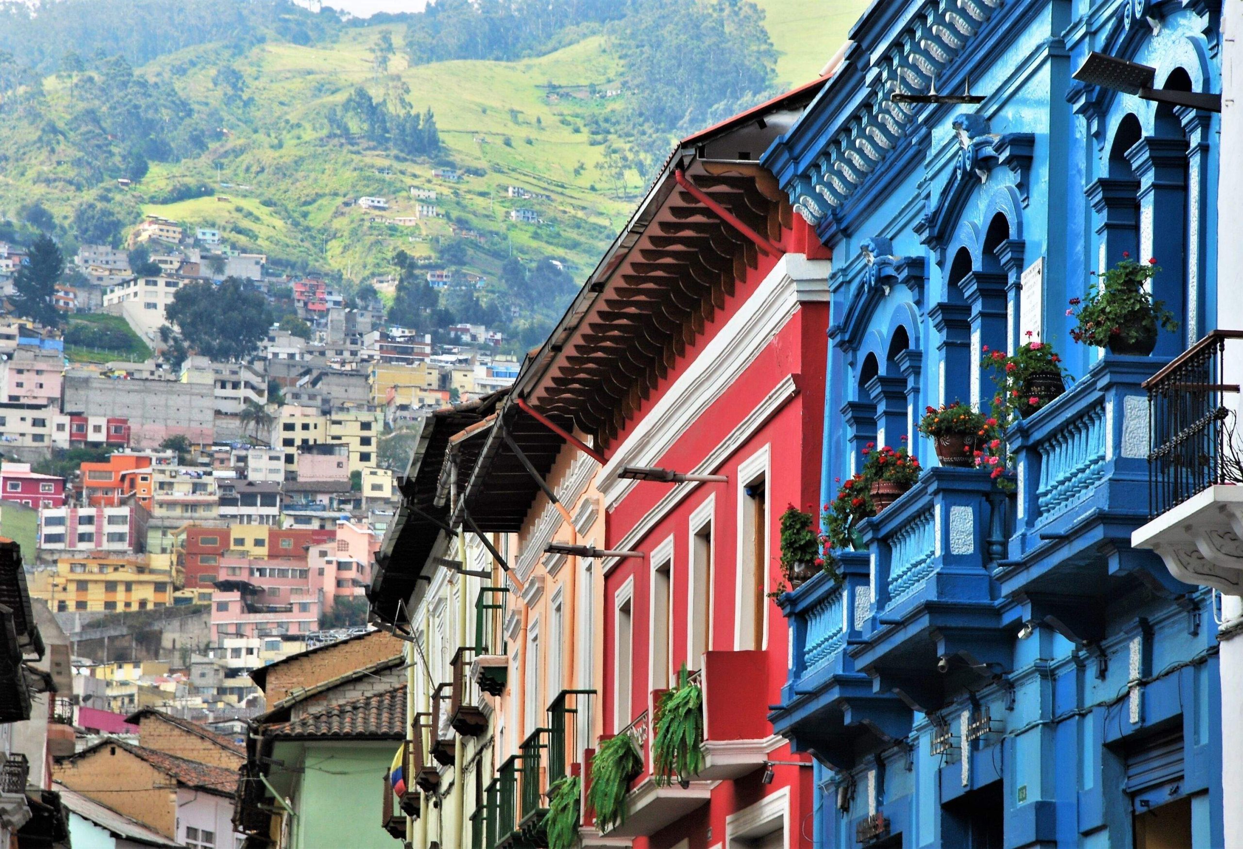 A row of colourful adjacent buildings with flower planters on its balconies.