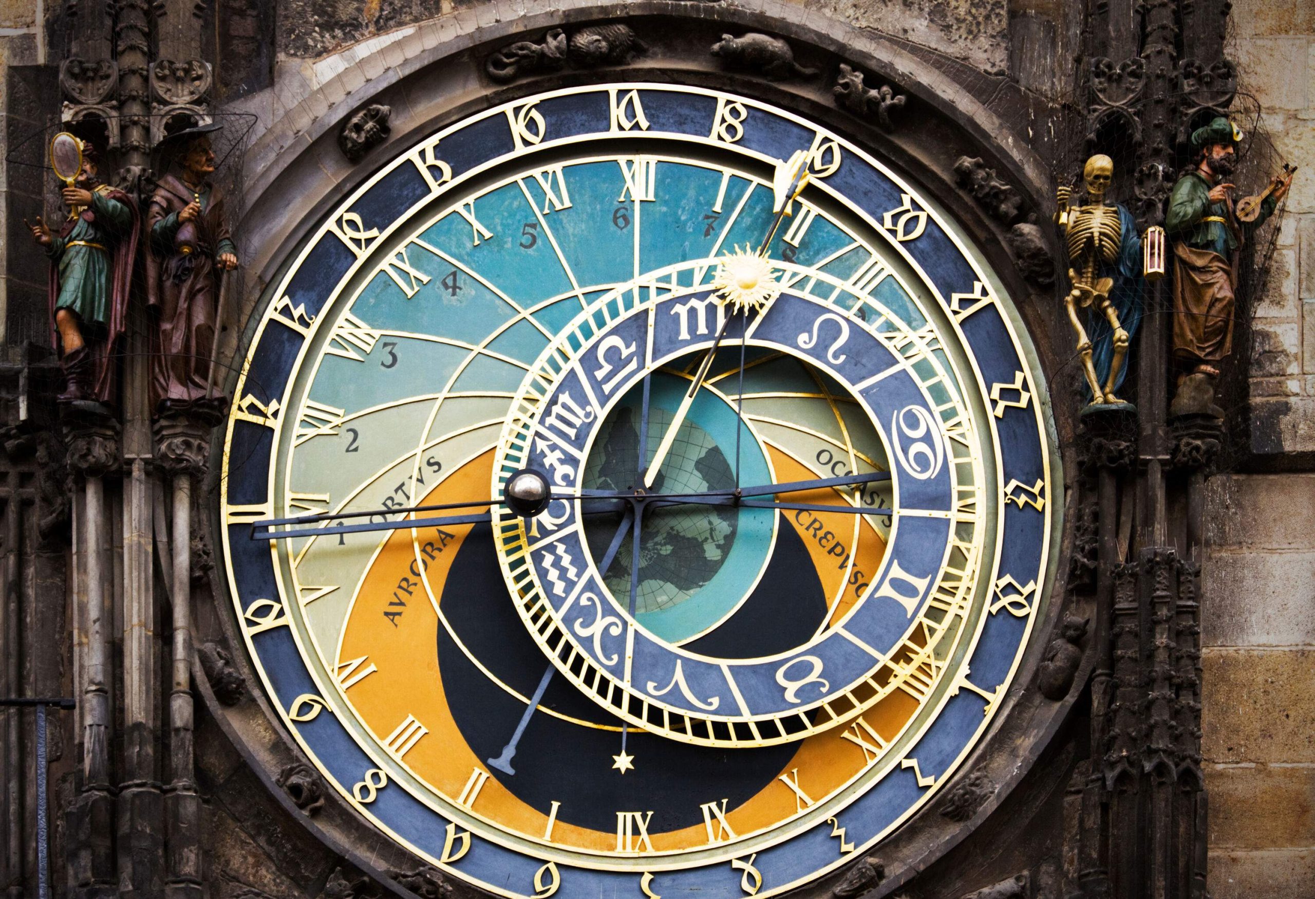 The Prague astronomical clock, adorned with Roman numerals and astronomical symbols, is flanked by intricate statues, including a personification of death and figures representing the twelve apostles.