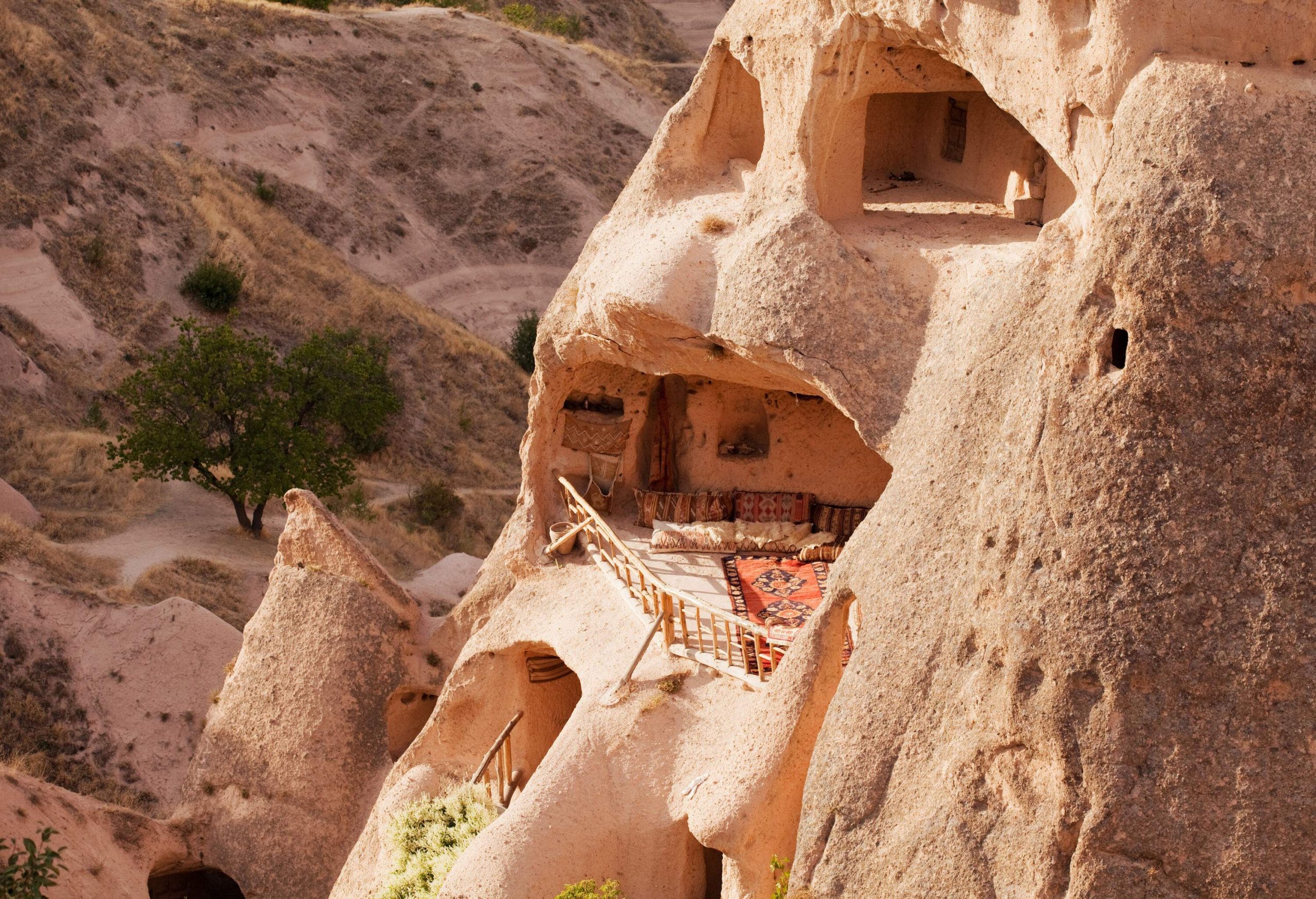 An accommodation inside a cave with a balcony overlooking a deserted slope.