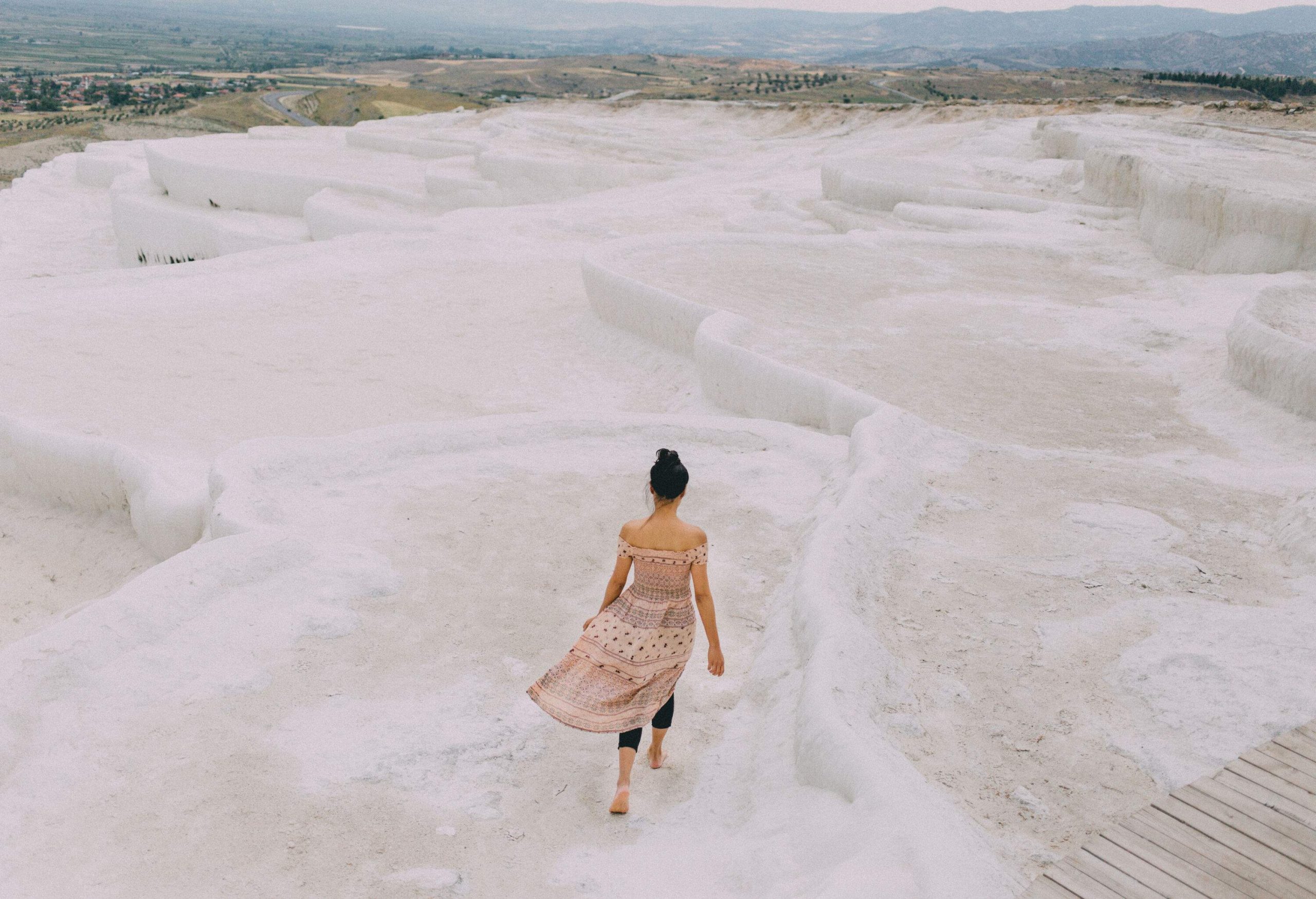 A lone individual walks along a mesmerising, snow-white limestone landscape, characterised by its terraced formations.