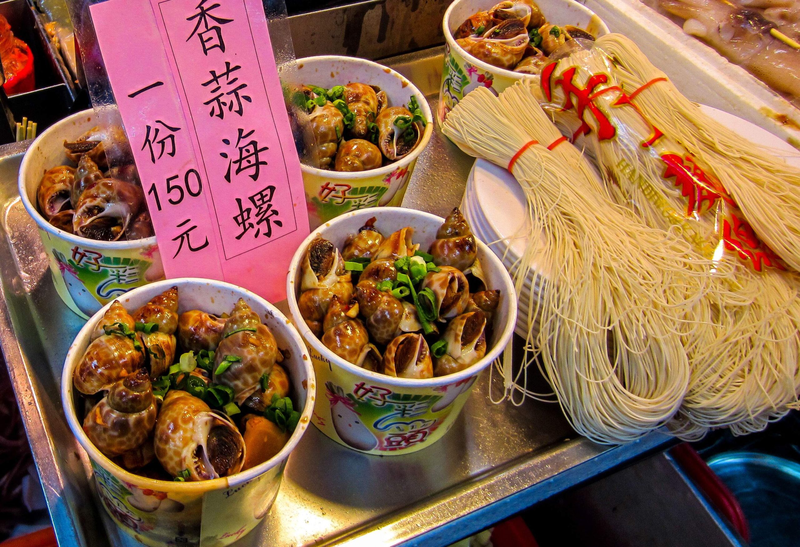 Display of enticing bowls filled with delectable snails and noodles, ready for sale, offering a unique and flavorful culinary experience.