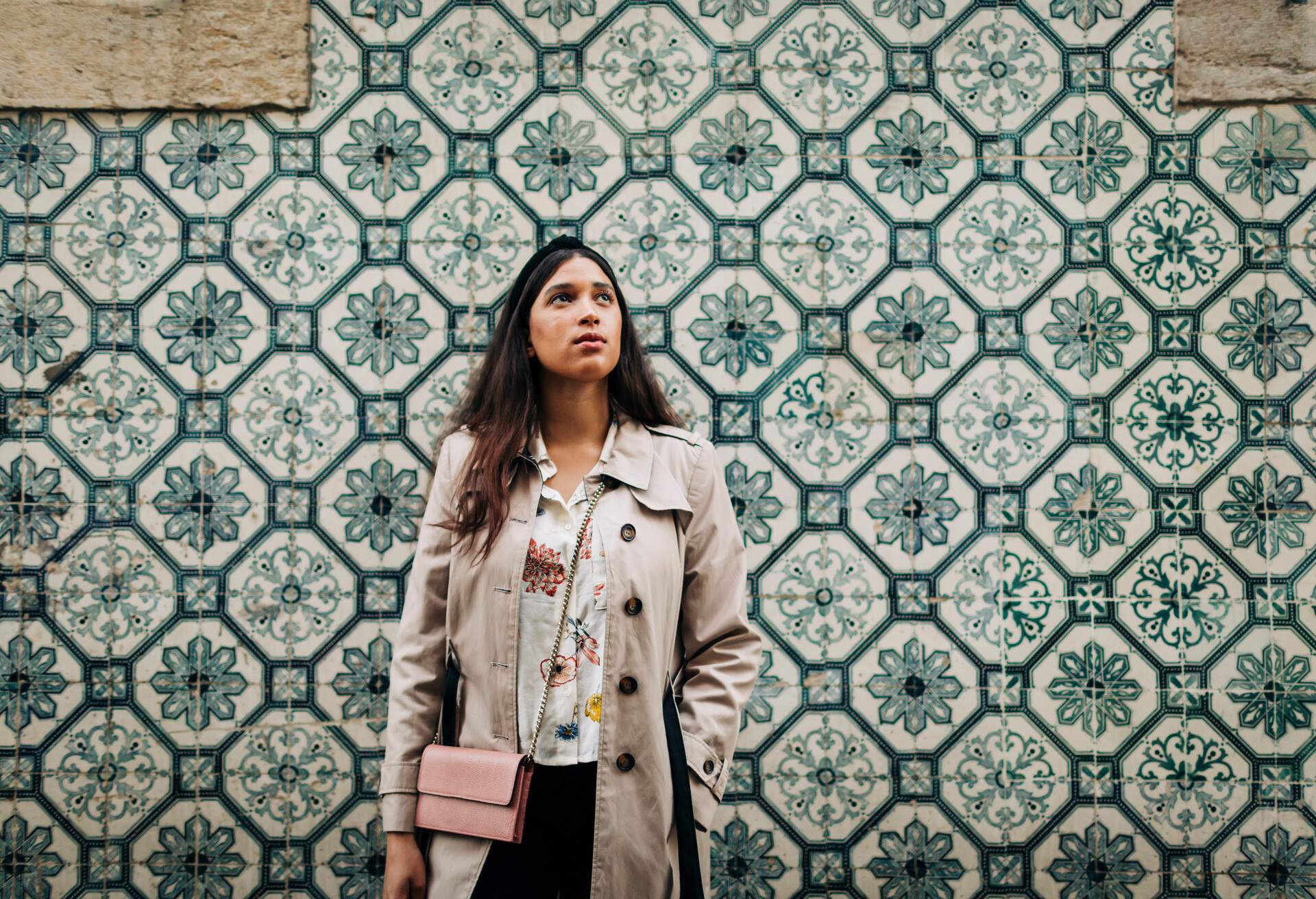 A beautiful woman in casual wear stands at a wall adorned with stylish tiles.