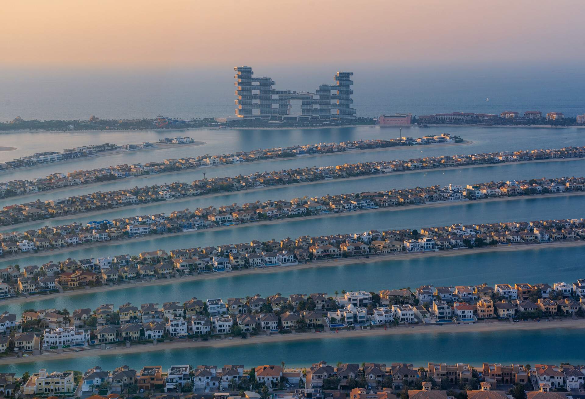 An evening shot of rows of houses on the artificial island 'The Palm' in Dubai with the big hotel 'Atlantis The Royal' in the background