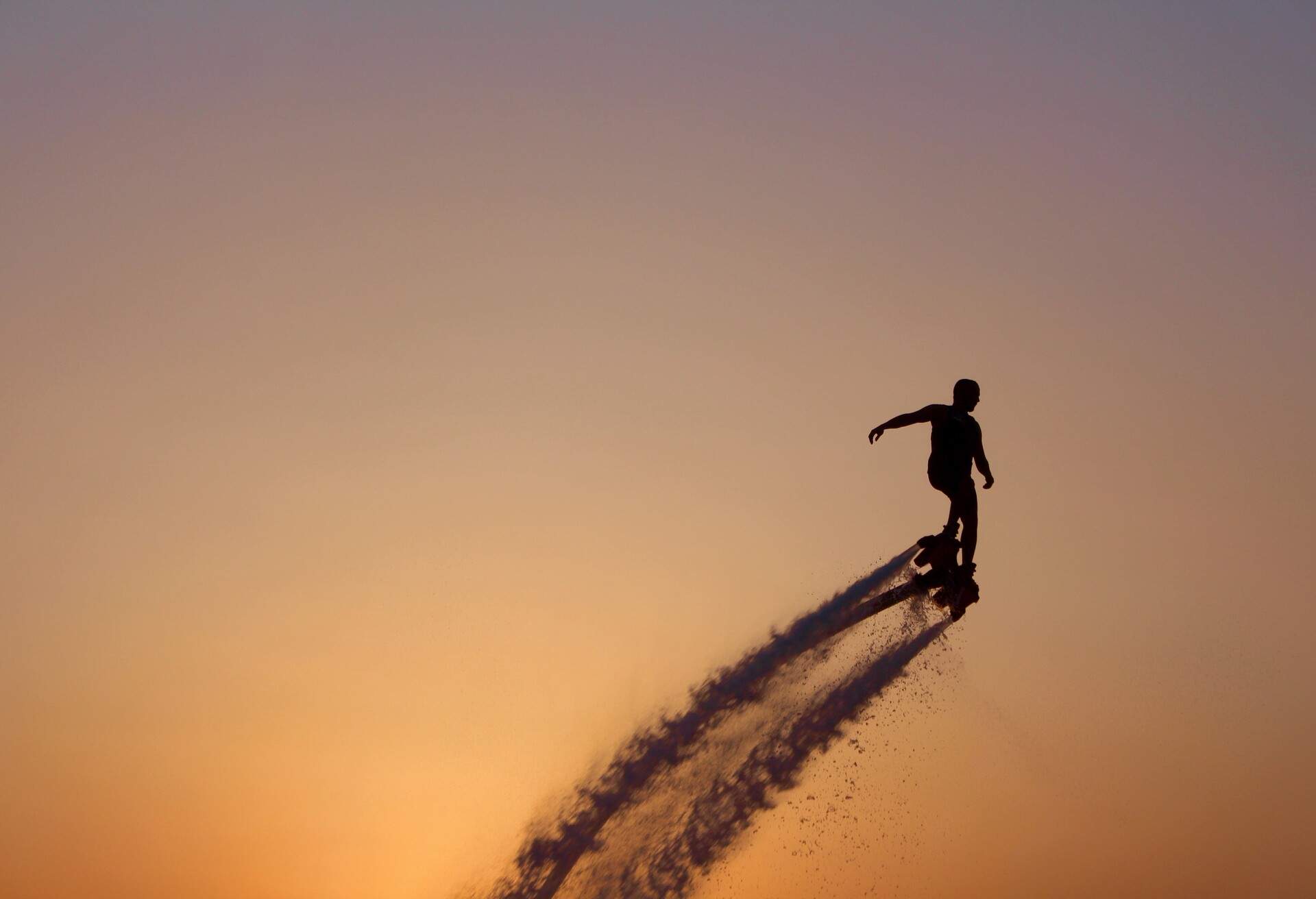 Silhouette of a man on a flyboard with the sunset as a backdrop