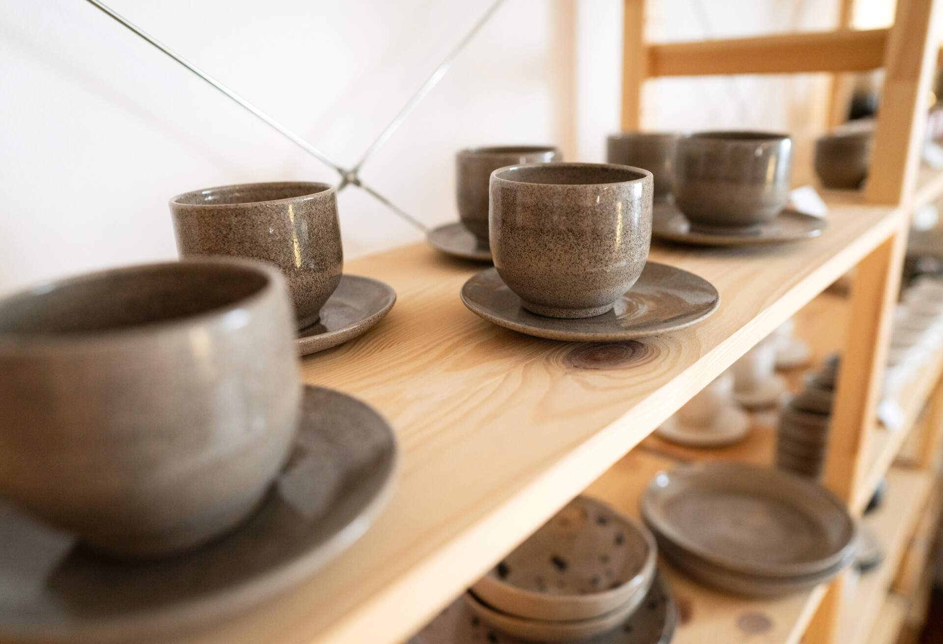 Grey ceramic coffee cups on a wood shelf in a homeware shop 