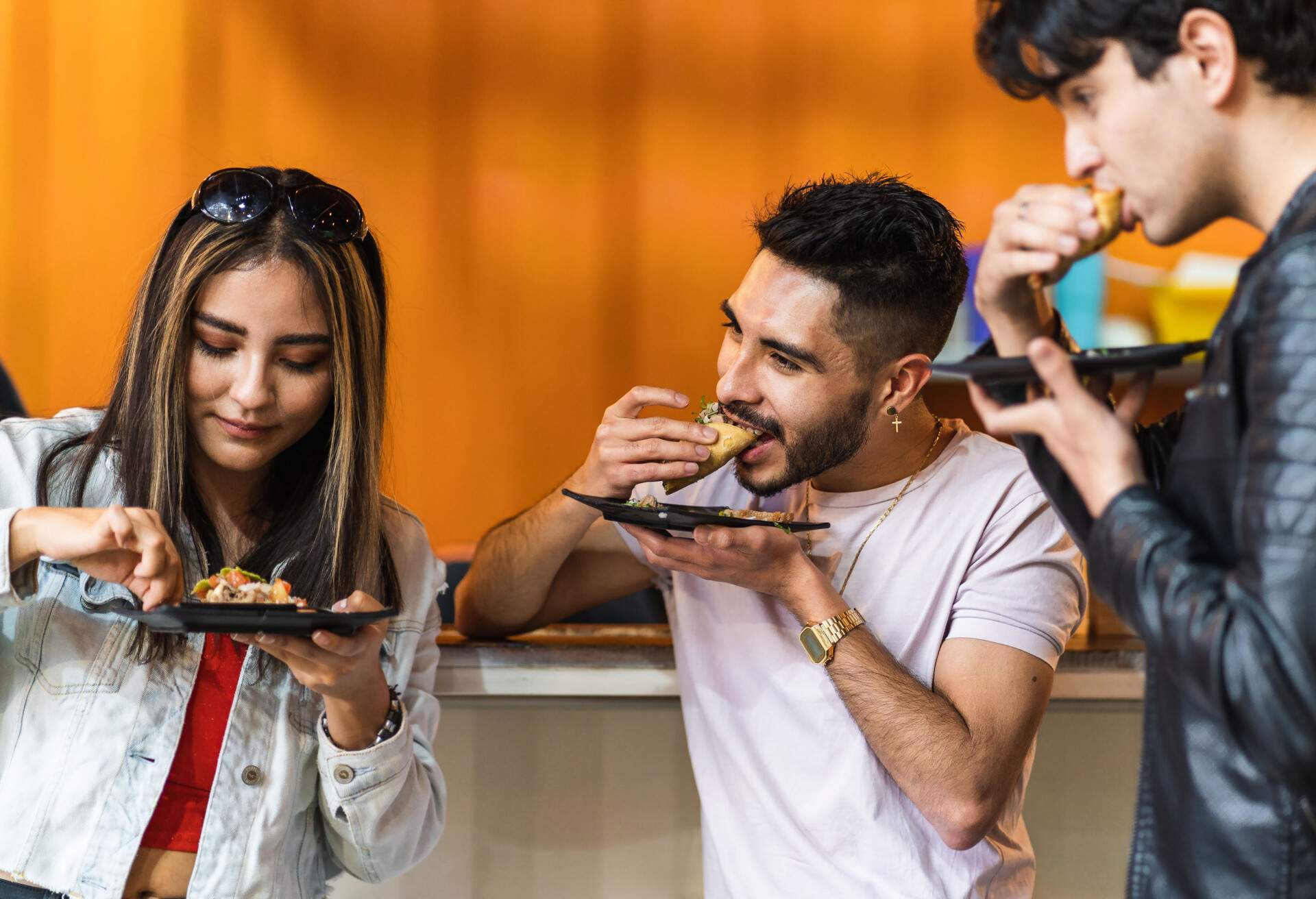 three latinos eating tacos in taqueria