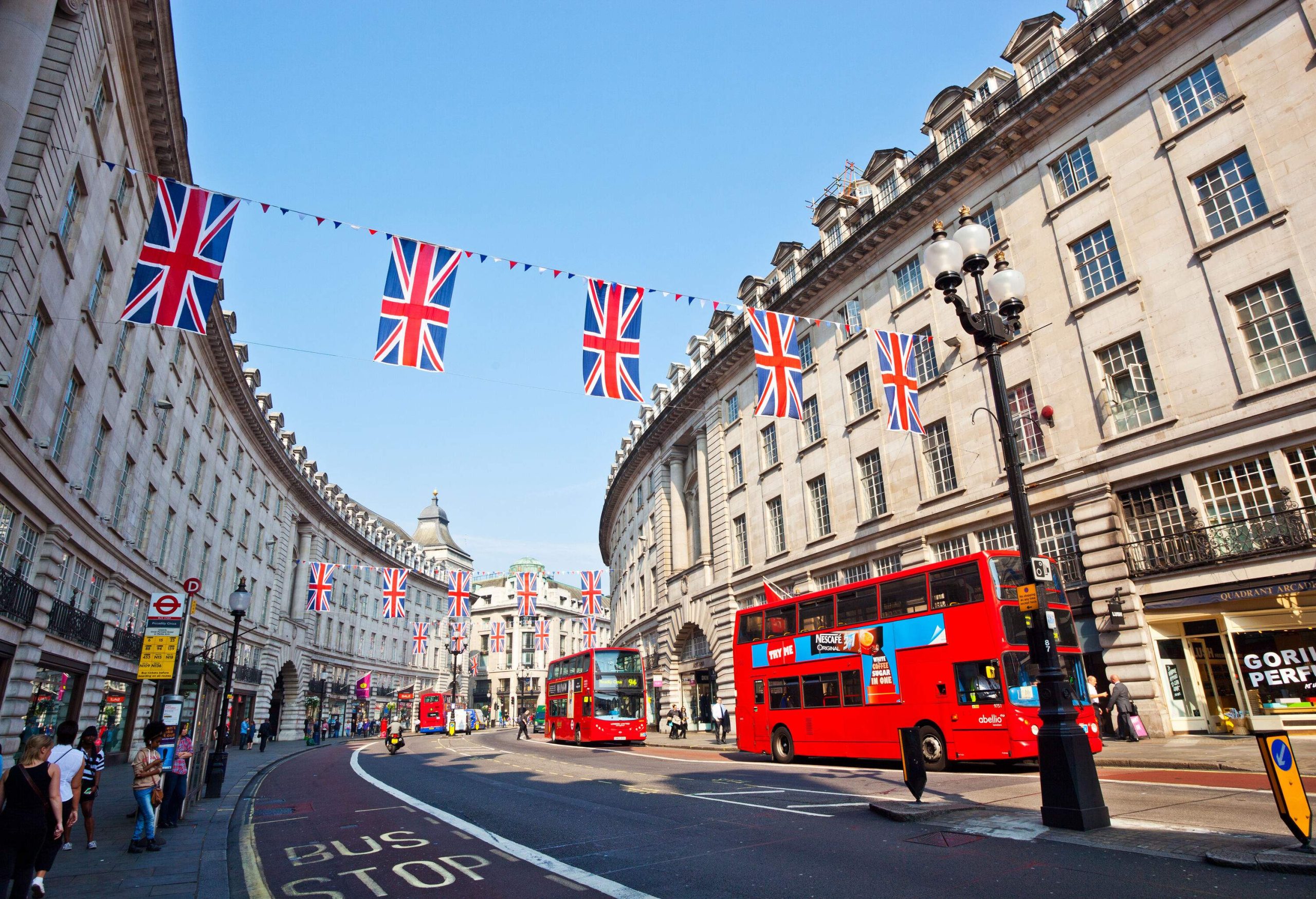 Regents St with red buses and bunting in London street.